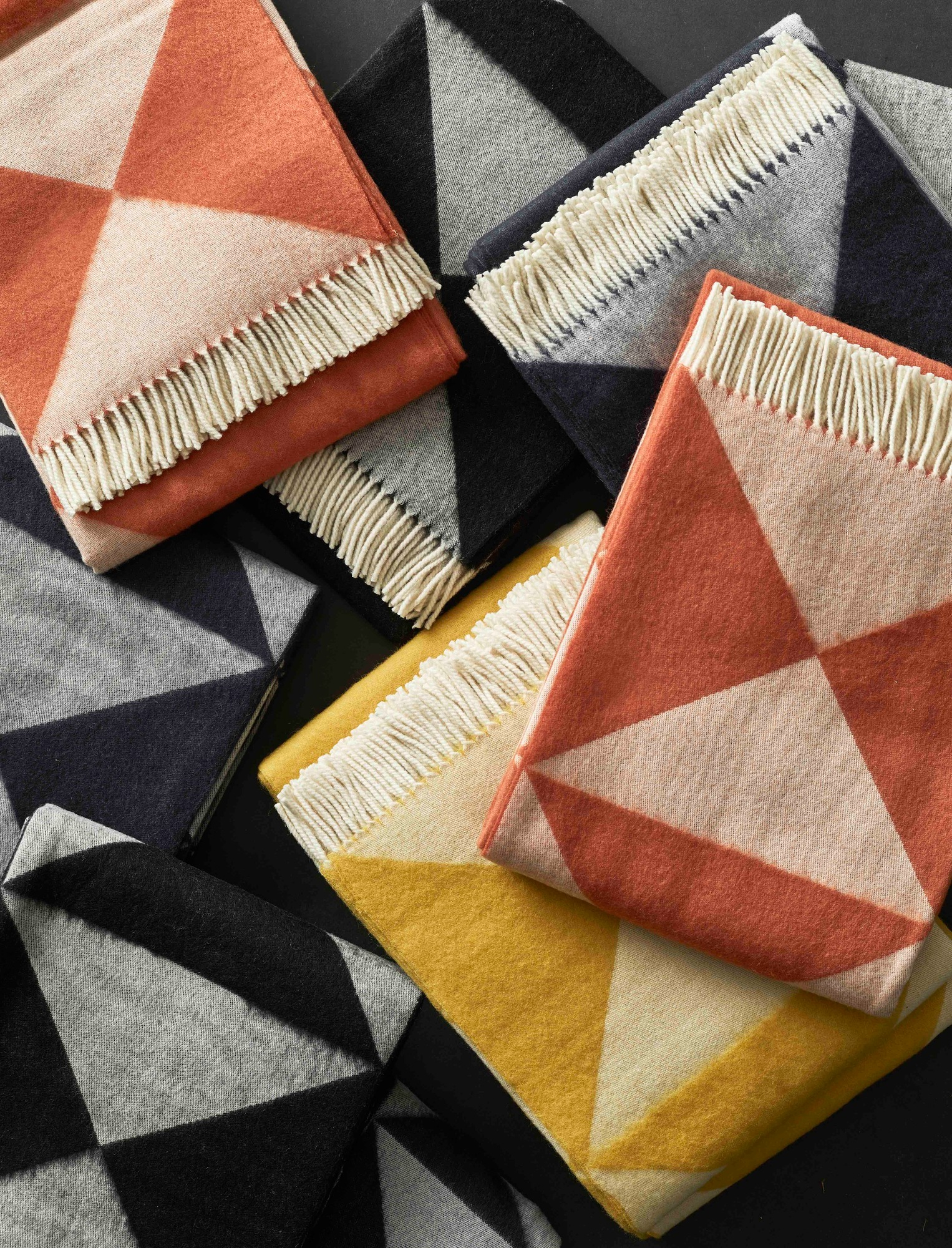 Nahaufnahme von gestapelten Verpan Mirror Throw Decken mit geometrischem Muster und Fransen.