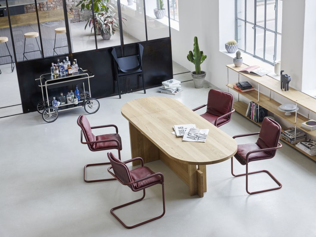 M4RS Tecta Barwagen in Schwarz mit Getränken, rotes Stuhlset und Holztisch in hellem Raum.