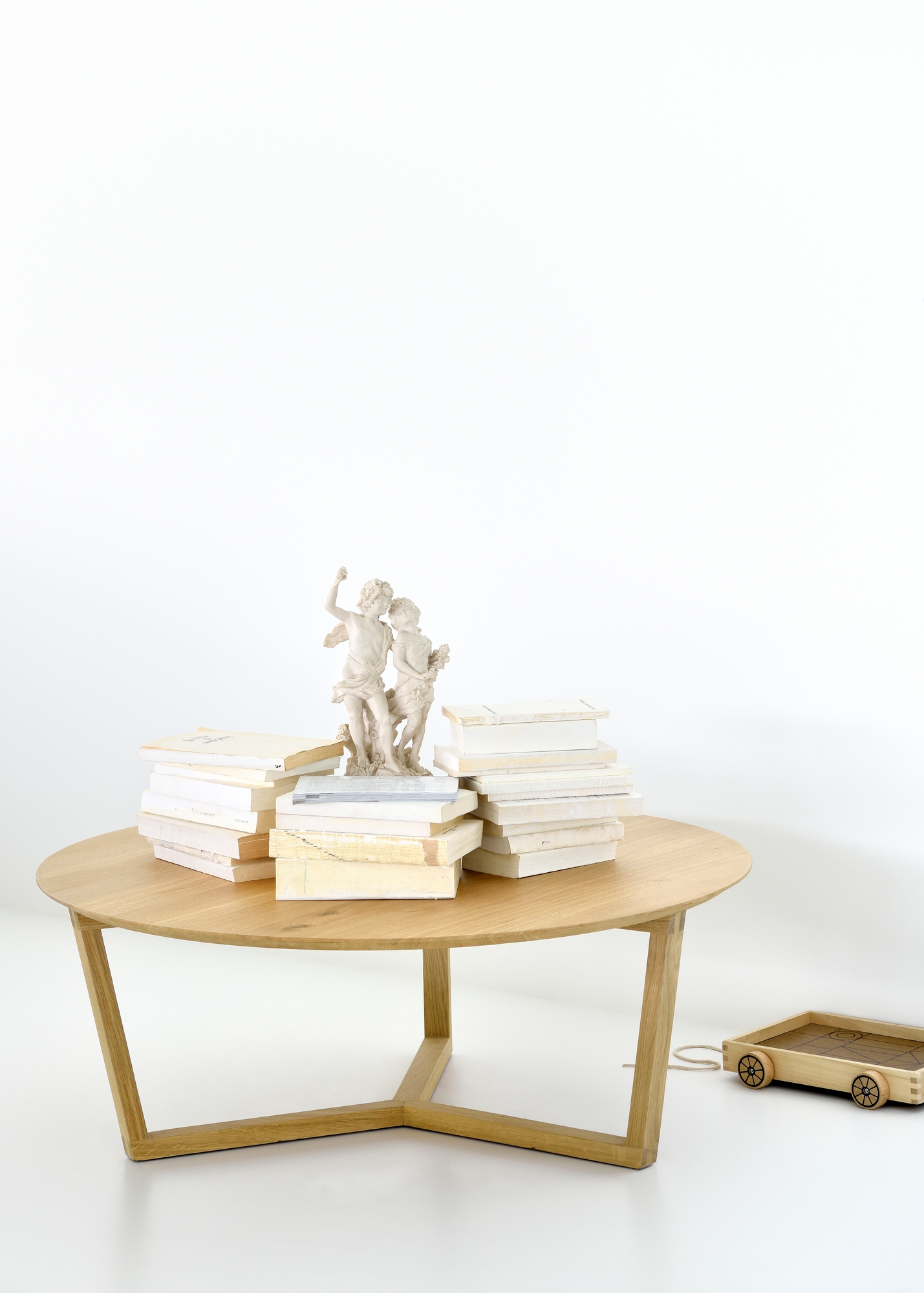 Ethnicraft Couchtisch Tripod aus Eiche mit Büchern und einer Skulptur dekoriert, minimalistisches Design.