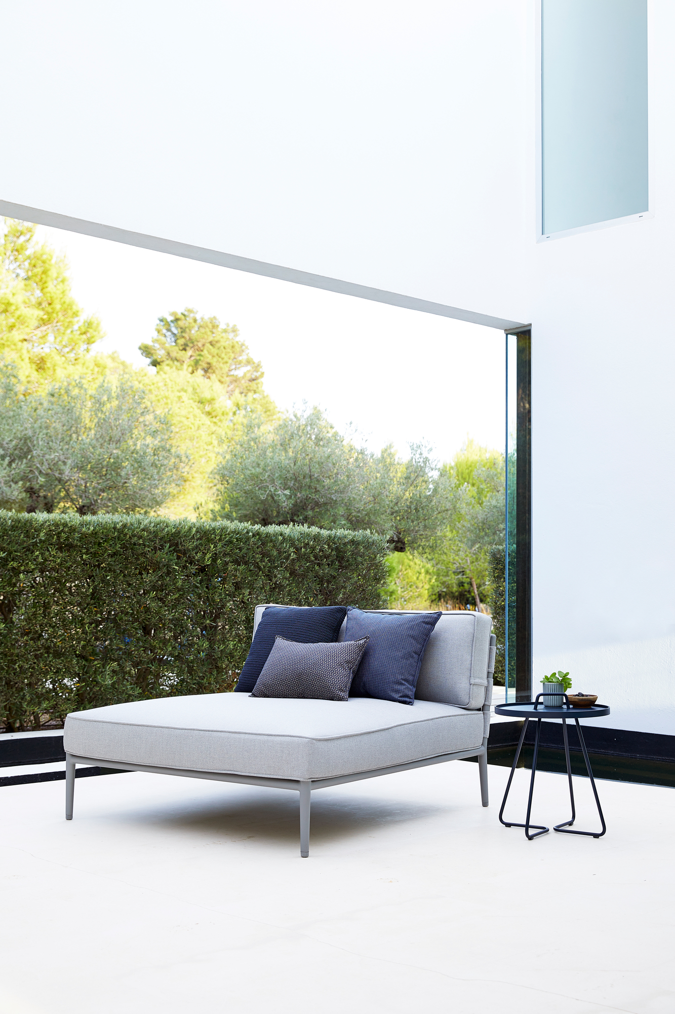 Conic AirTouch Daybed von Cane-Line: Graues Outdoor Daybed mit Kissen und Beistelltisch.