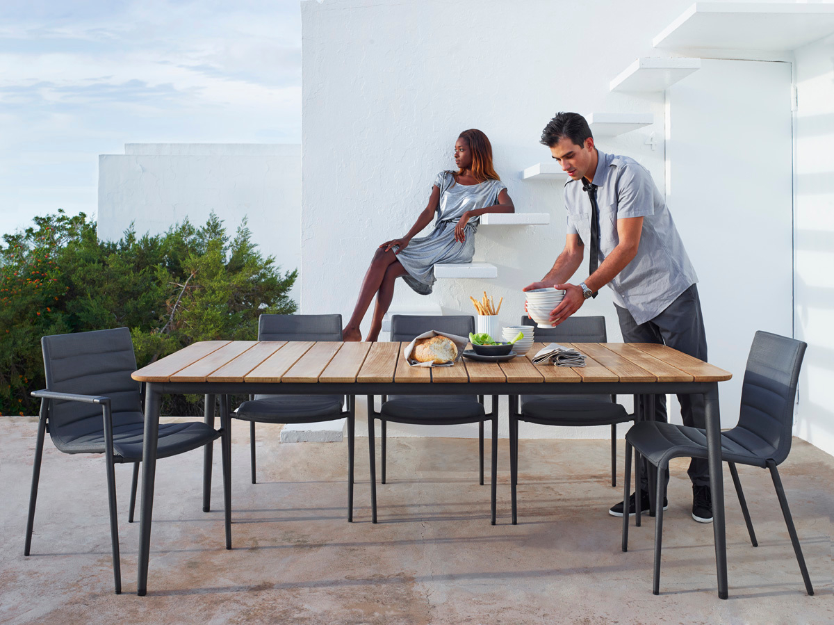 Core Outdoor Esstisch aus Teak von Cane-Line mit grauen Stühlen für stilvolles Essen im Freien.