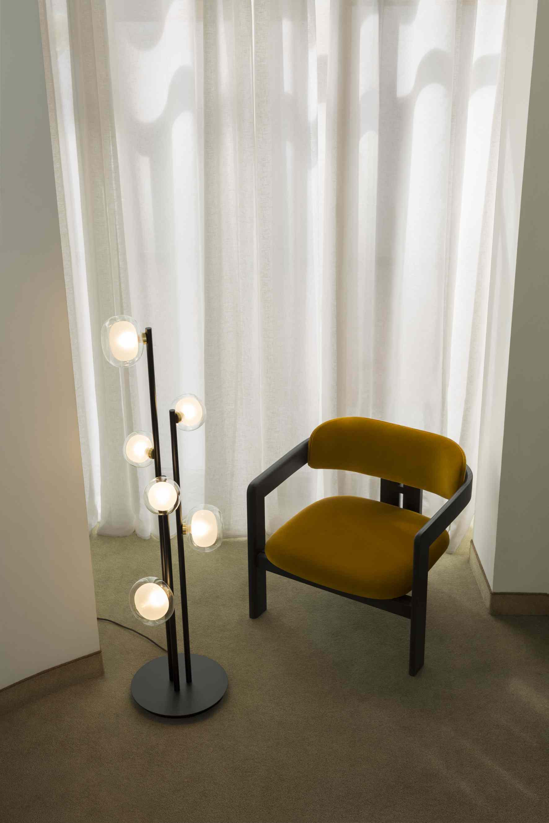 Tooy Nabila Stehleuchte mit sechs Glaskugeln neben einem gelben Sessel im Wohnzimmer.