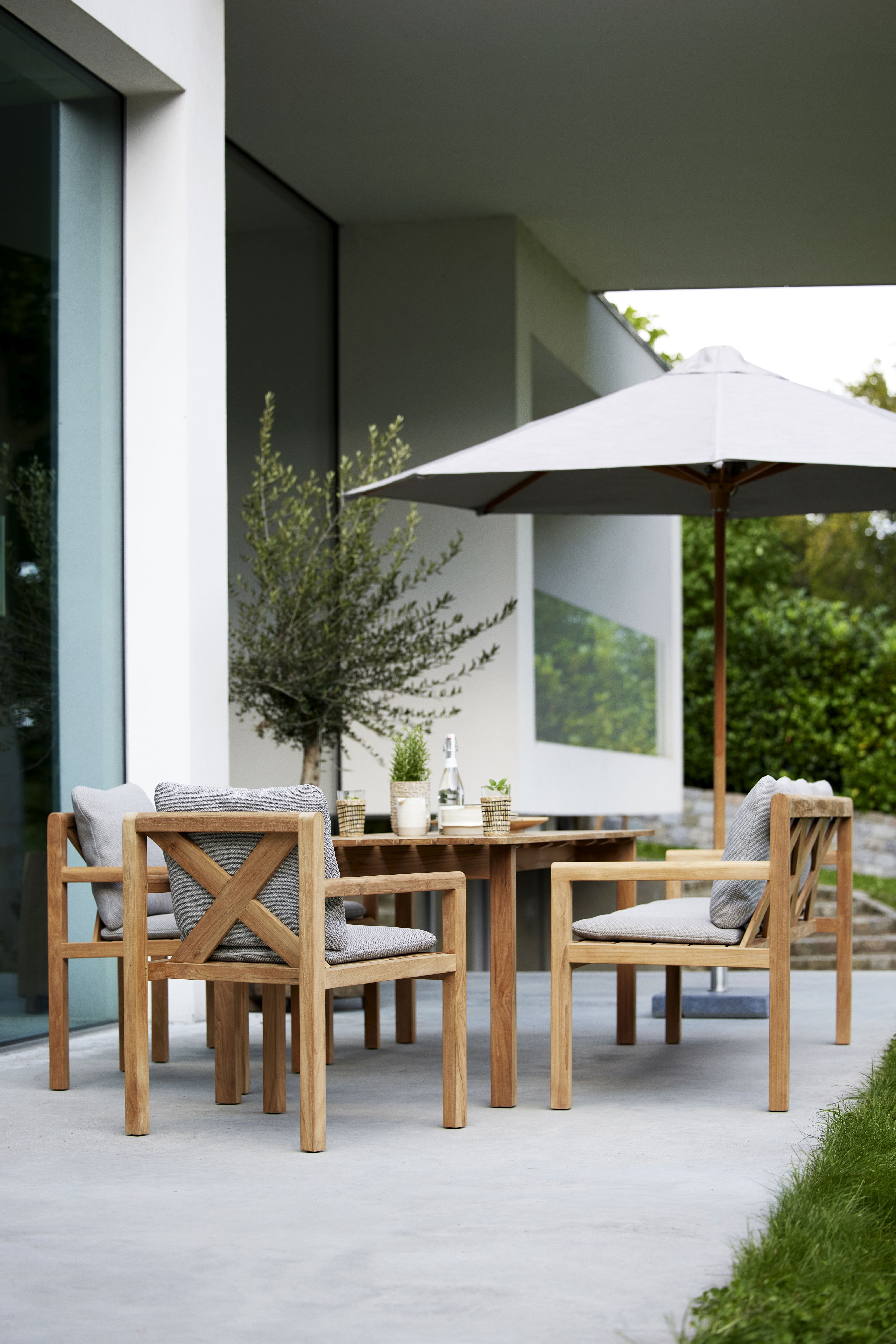 Grace Esstisch von Cane-Line aus Teakholz mit Stühlen und Sonnenschirm für den Garten.