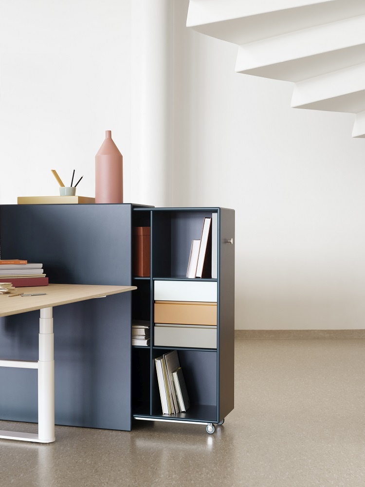 HiLow höhenverstellbarer Arbeitstisch von Montana mit blauem Sideboard und Rollcontainer für Büroorganisation.