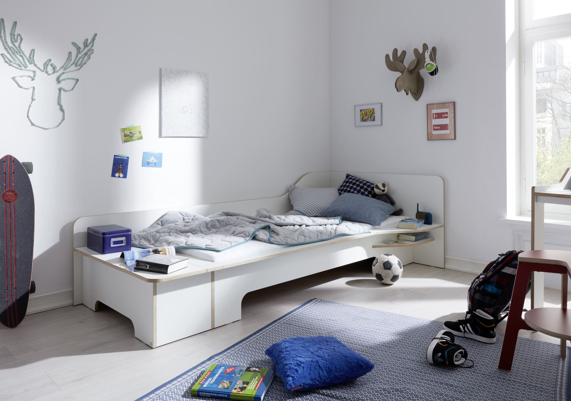 Helles Kinderzimmer mit Plane Einzelbett von Müller Möbelwerkstätten, weißem Bettgestell und verspielter Dekoration.