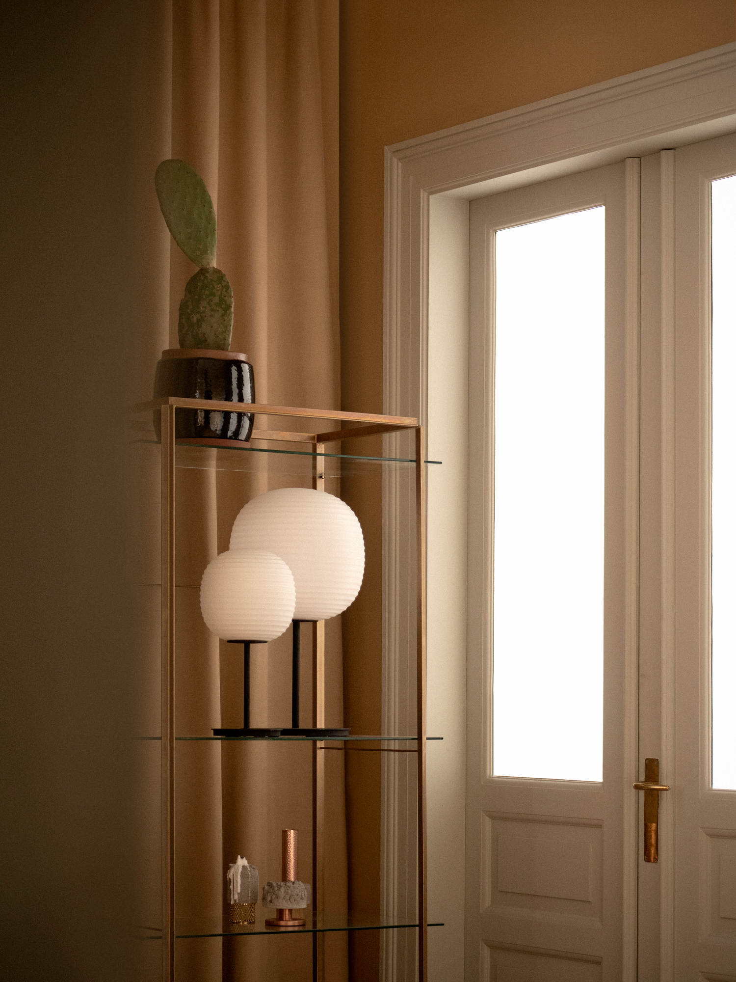 Zwei New Works Lantern Tischleuchten auf einem Regal mit Dekoration, stimmungsvolle Beleuchtung.