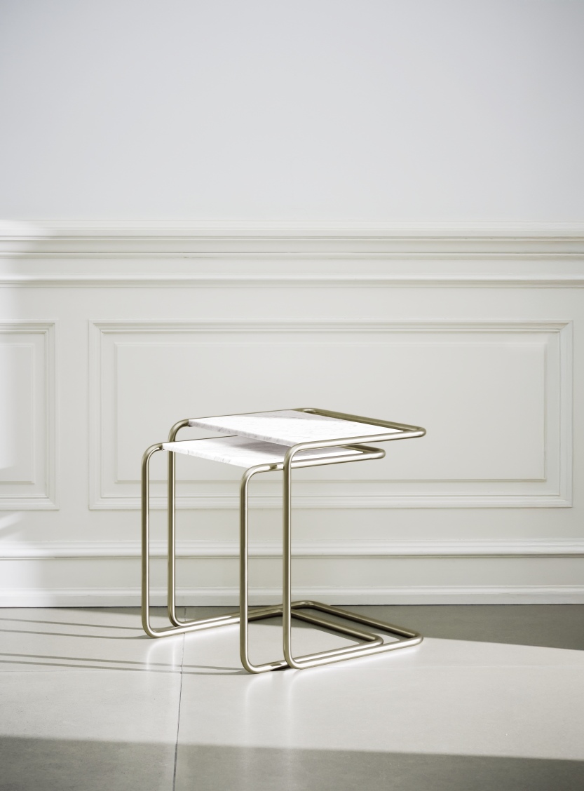 JS. Thonet B97 Beistelltisch: Zwei goldfarbene, minimalistische Tische mit Marmorplatte vor weißer Wand.