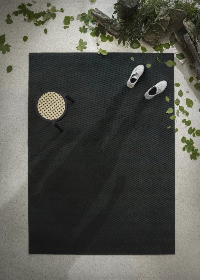 Dunkelbrauner Row Teppich von Northern, Medium Größe, mit Struktur, Stuhl und Schuhen.