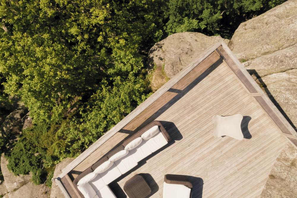 Draufsicht: Mariposa Outdoor Sessel auf Holzterrasse mit Lounge-Möbeln und Kissen.