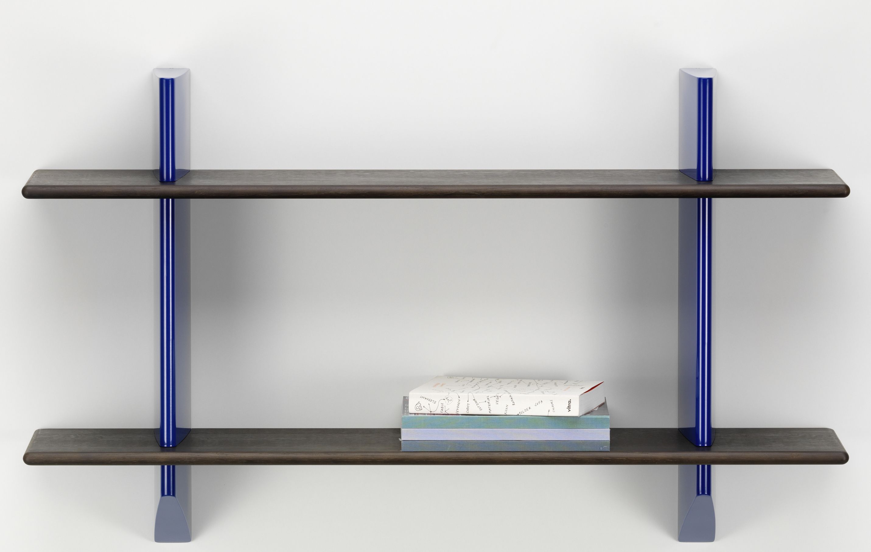 Vitra Wandregal Rayonnage Mural mit Eiche dunkel und blauen Elementen, Bücher auf der unteren Ablage.