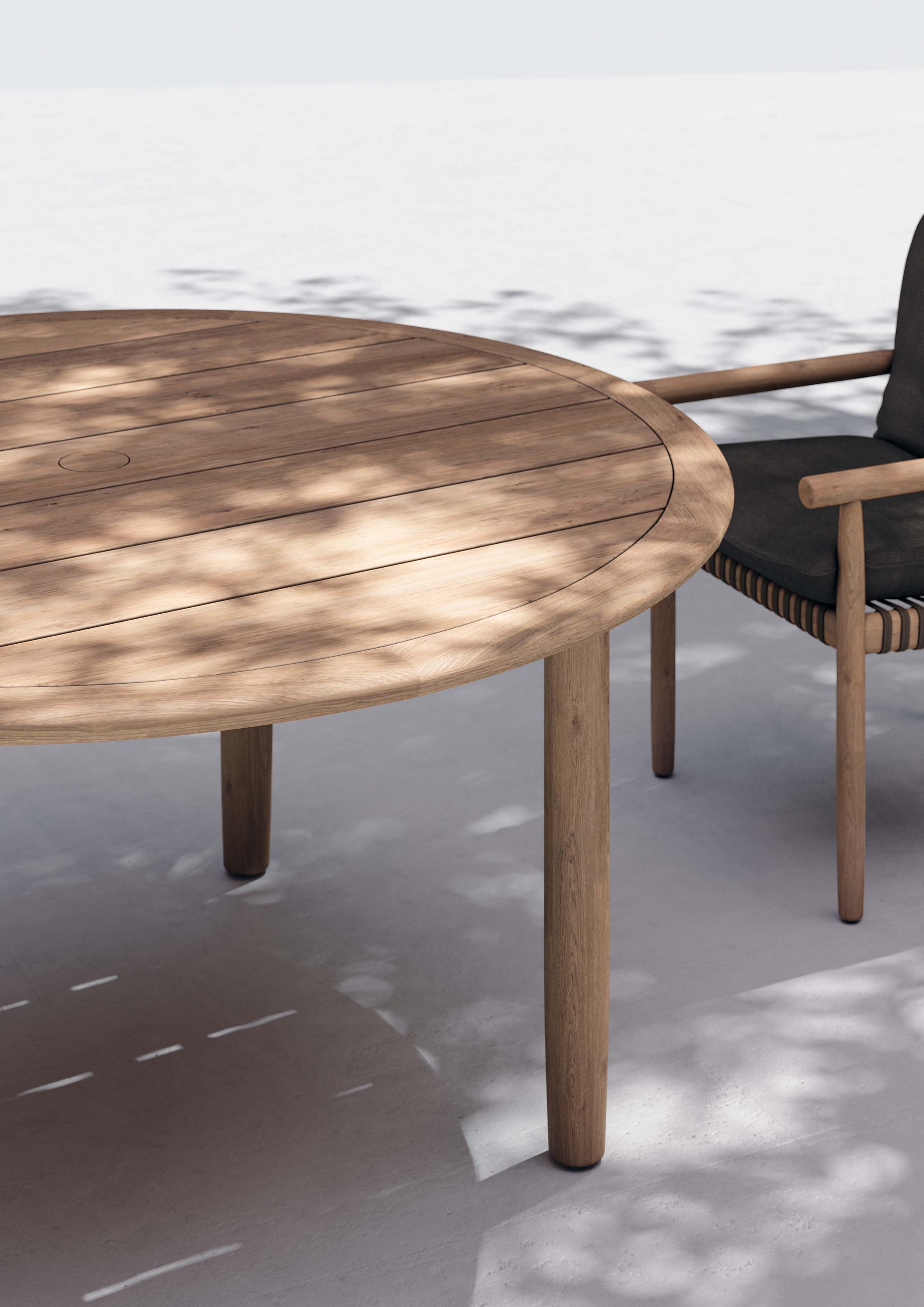 Nahaufnahme eines Tibbo Armlehnstuhls von Dedon mit rundem Holztisch im Außenbereich.