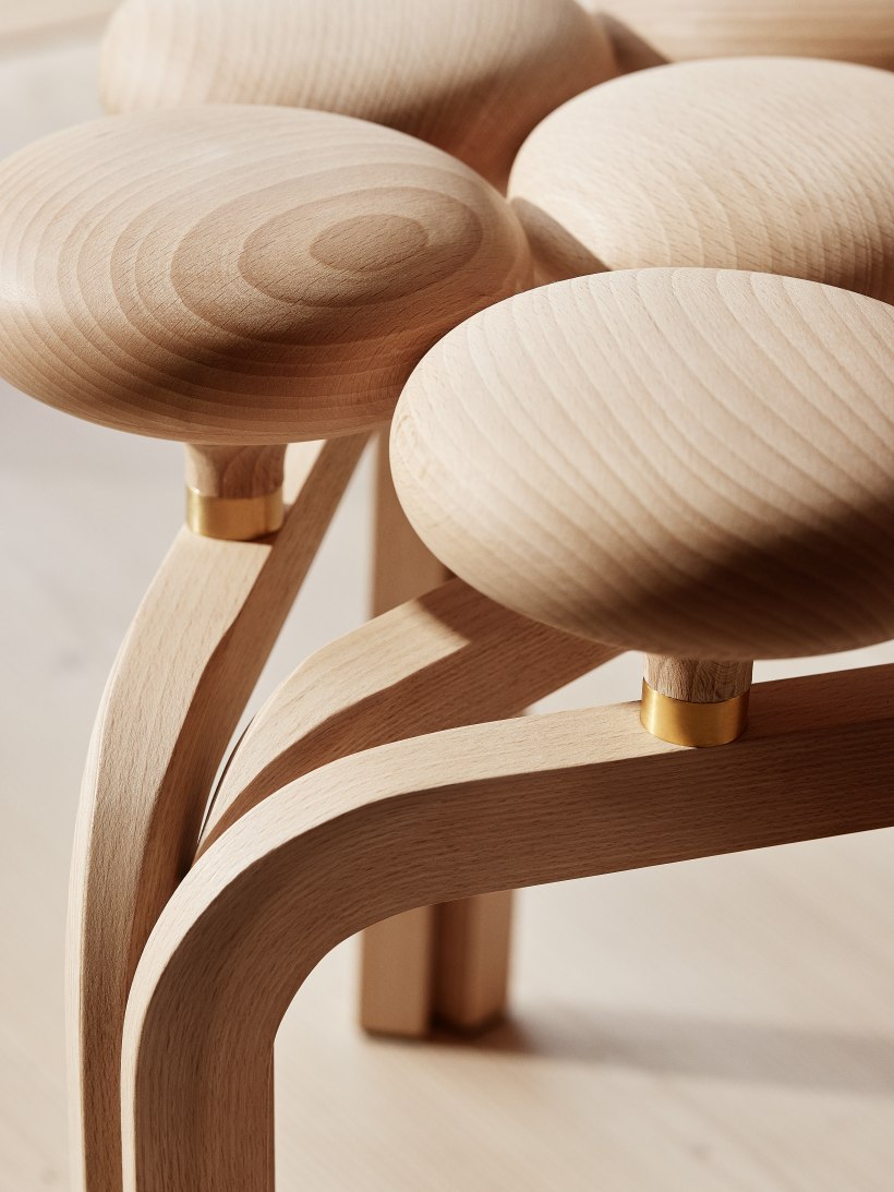 Detailaufnahme des Fritz Hansen Utzon Stool Hockers aus hellem Holz mit goldenen Akzenten.