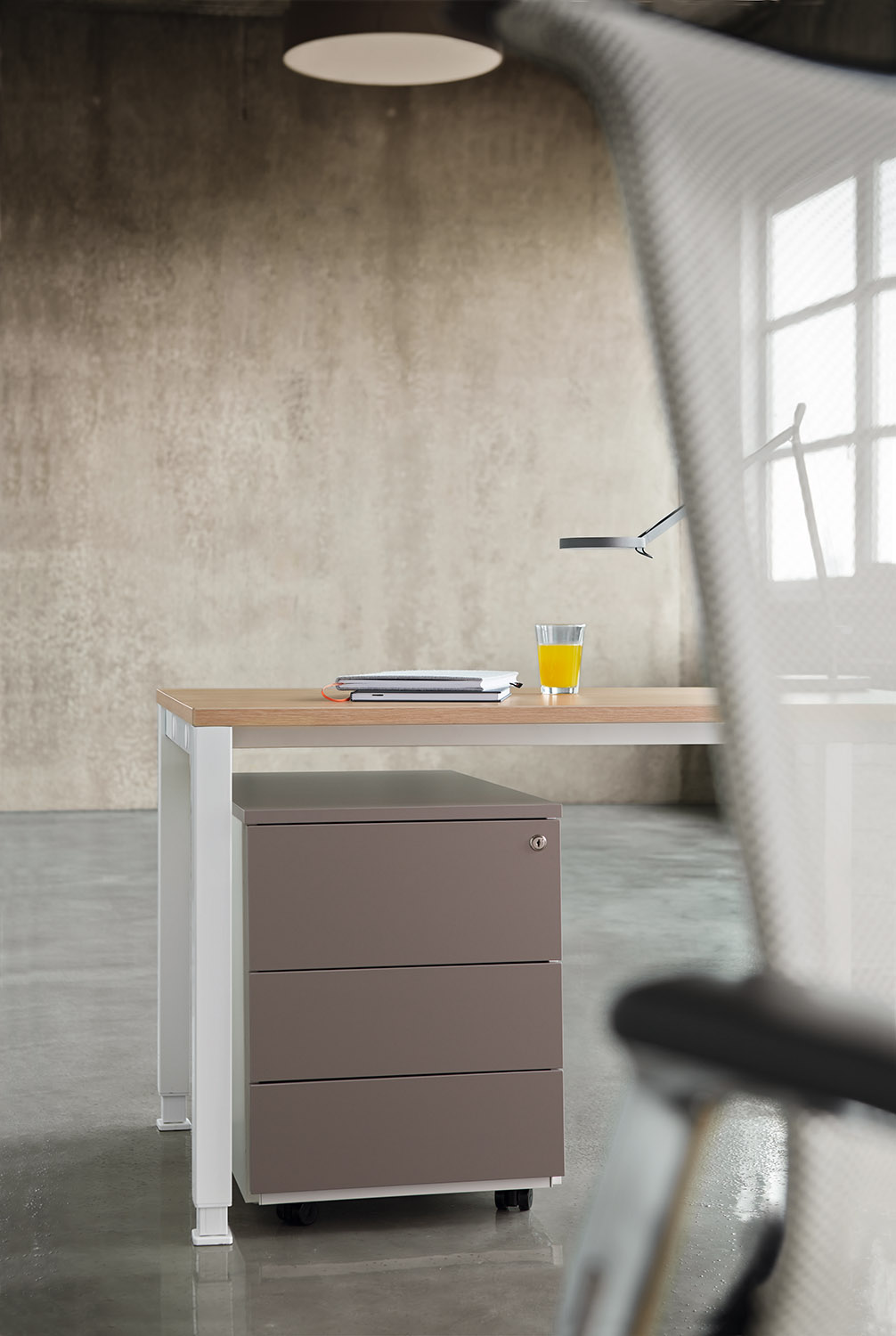 ECO.S Rollcontainer von König+Neurath mit drei Schubladen in Grau unter einem Schreibtisch.