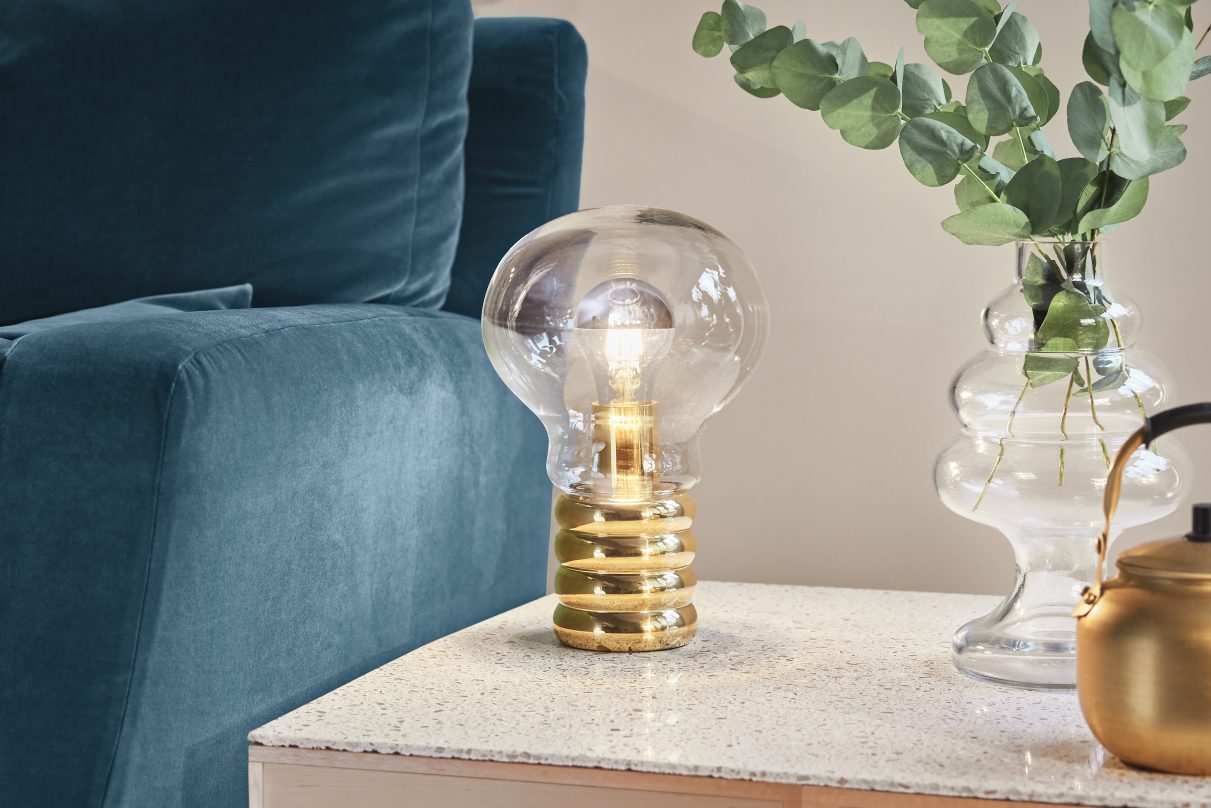 Nahaufnahme der Bulb Tischleuchte von Ingo Maurer mit goldenem Sockel und Glühbirne.