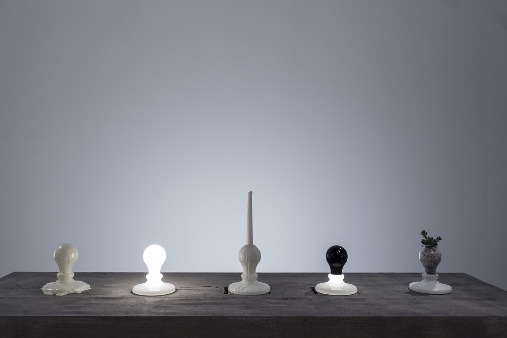 Fünf Foscarini Light Bulb Tavolo LED Tischleuchten in Weiß und Schwarz auf einem Tisch.