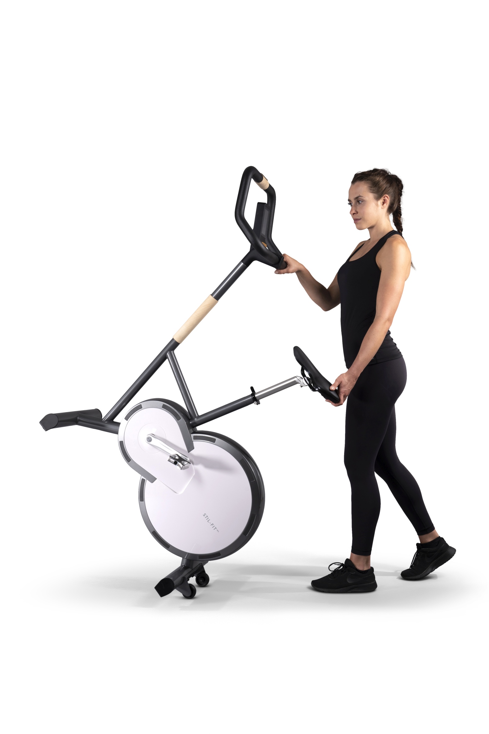 Frau schiebt stilvollen Heimtrainer mit Holzdetails und digitalem Display für Fitness zu Hause.