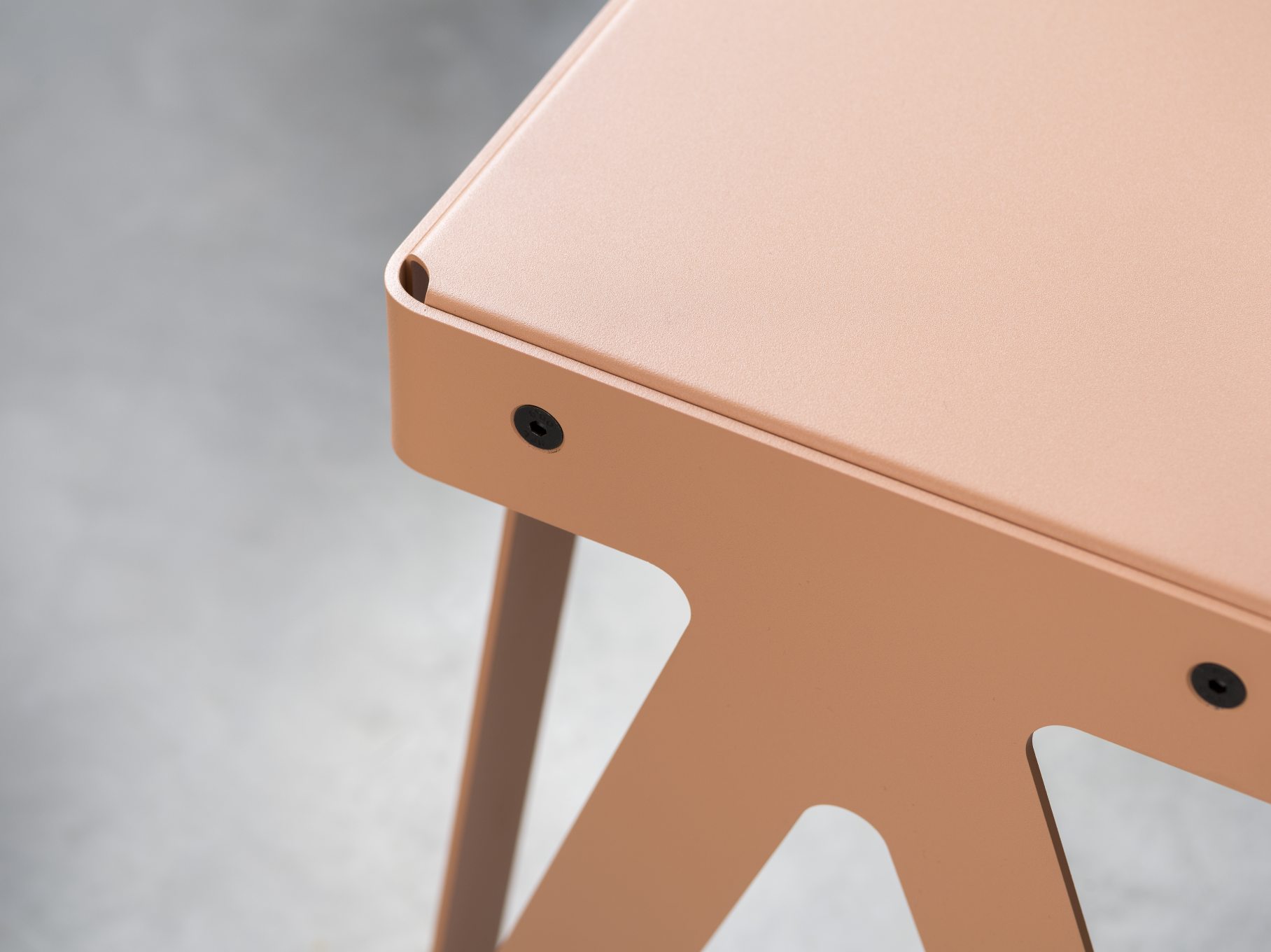 Detailaufnahme der Lloyd Bank: Metallgestell in Lachsfarbe, modernes Design, Indoor Sitzbank für Wohnraum und Büro.