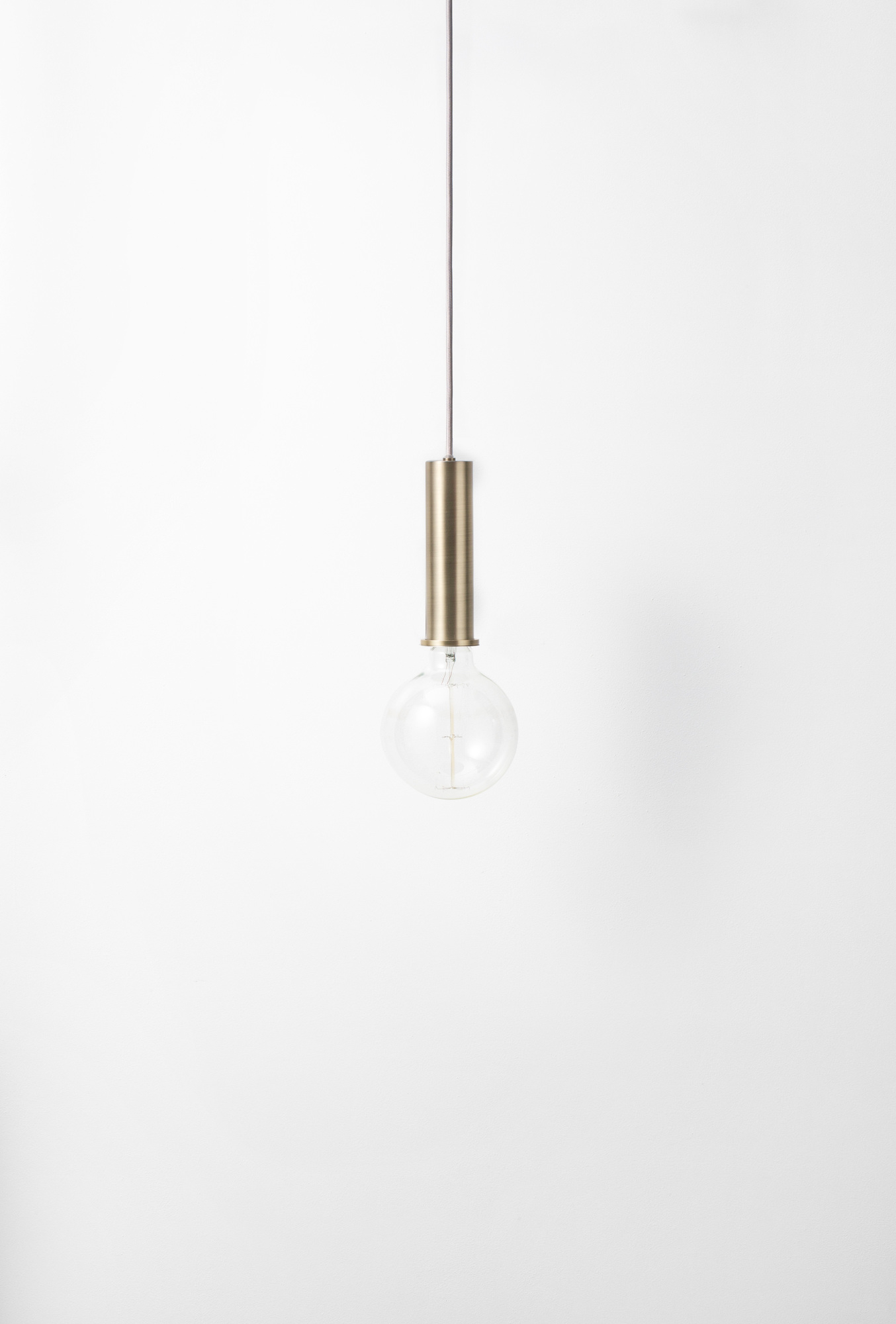 Nahaufnahme der Ferm Living Collect Pendelleuchte in hoch Messing mit Glühbirne.