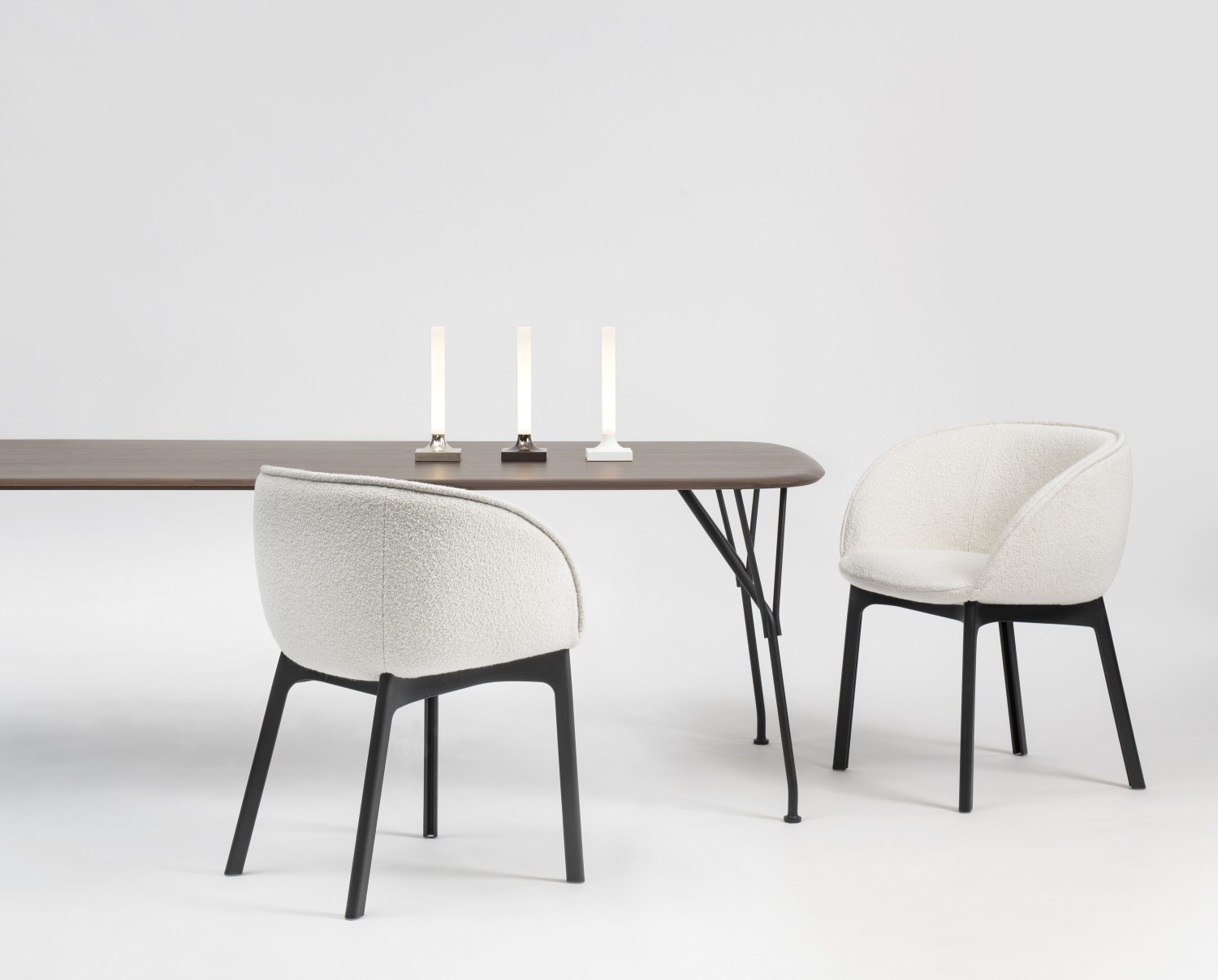 Tisch mit Stühlen und drei Goodnight Akkuleuchten von Kartell in verschiedenen Farben.