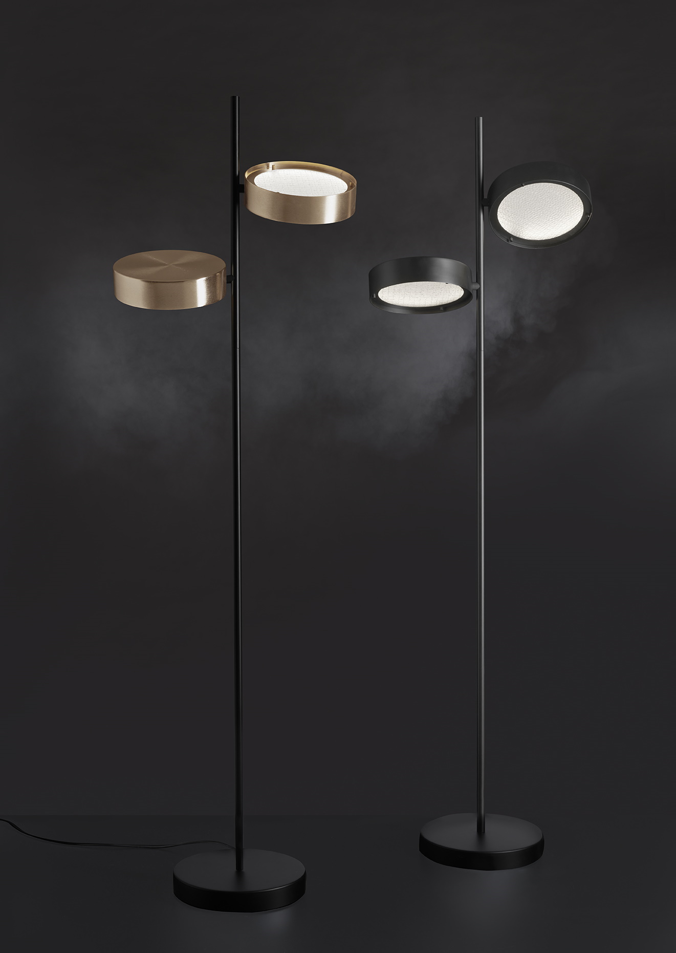 Zwei moderne Berlin Stehleuchten von Oluce in Gold und Schwarz vor dunklem Hintergrund.