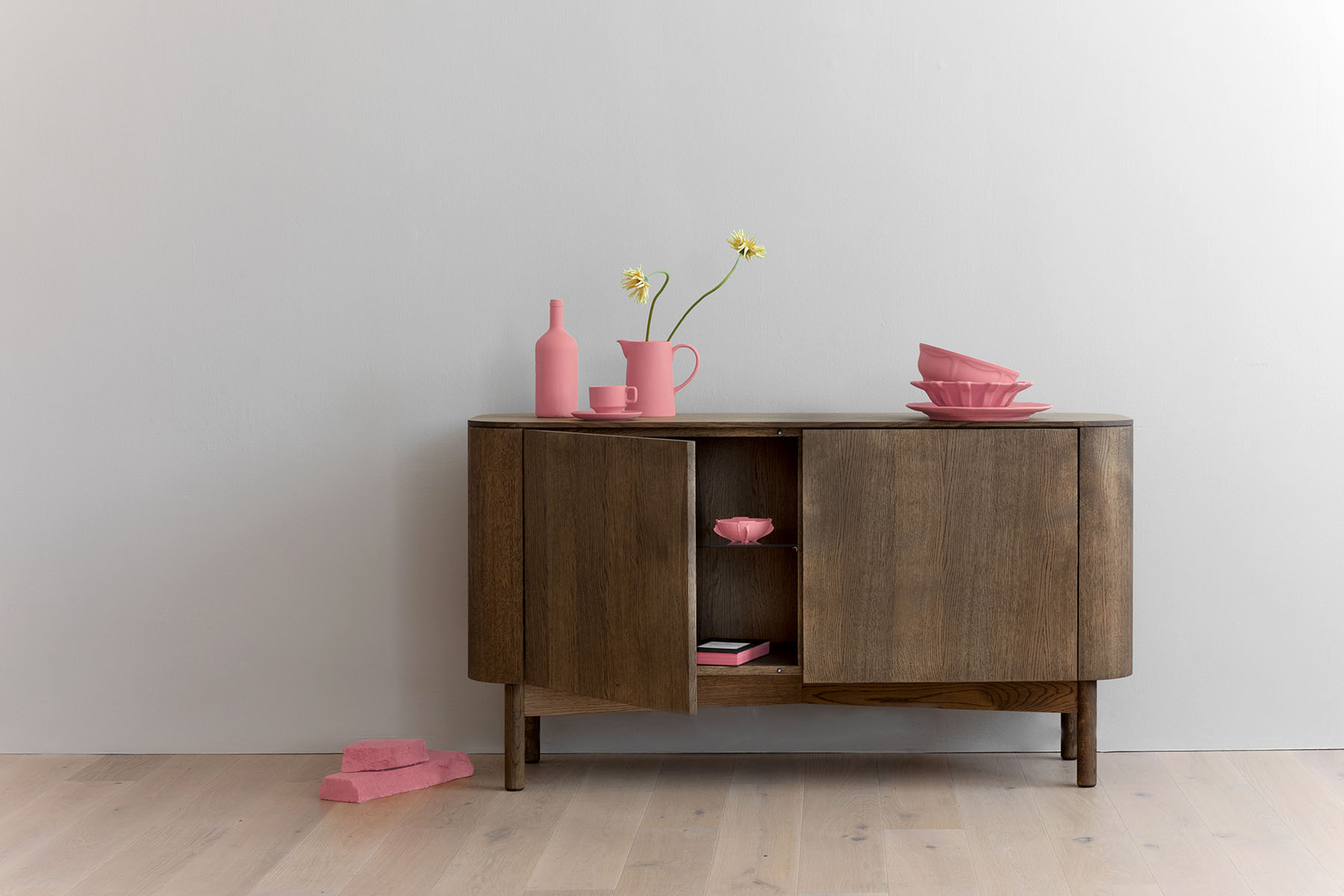 Loud Sideboard aus Eiche hell von Northern mit offener Tür und pinker Deko.