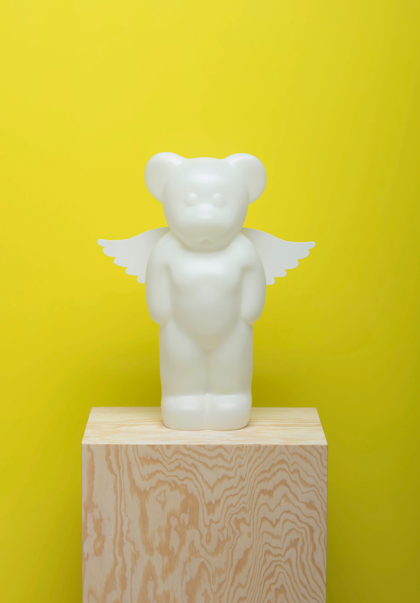 Weiße Lumibär Stehleuchte mit Flügeln auf einem Holzsockel vor gelbem Hintergrund. LED-Lampe, Kinderzimmer.