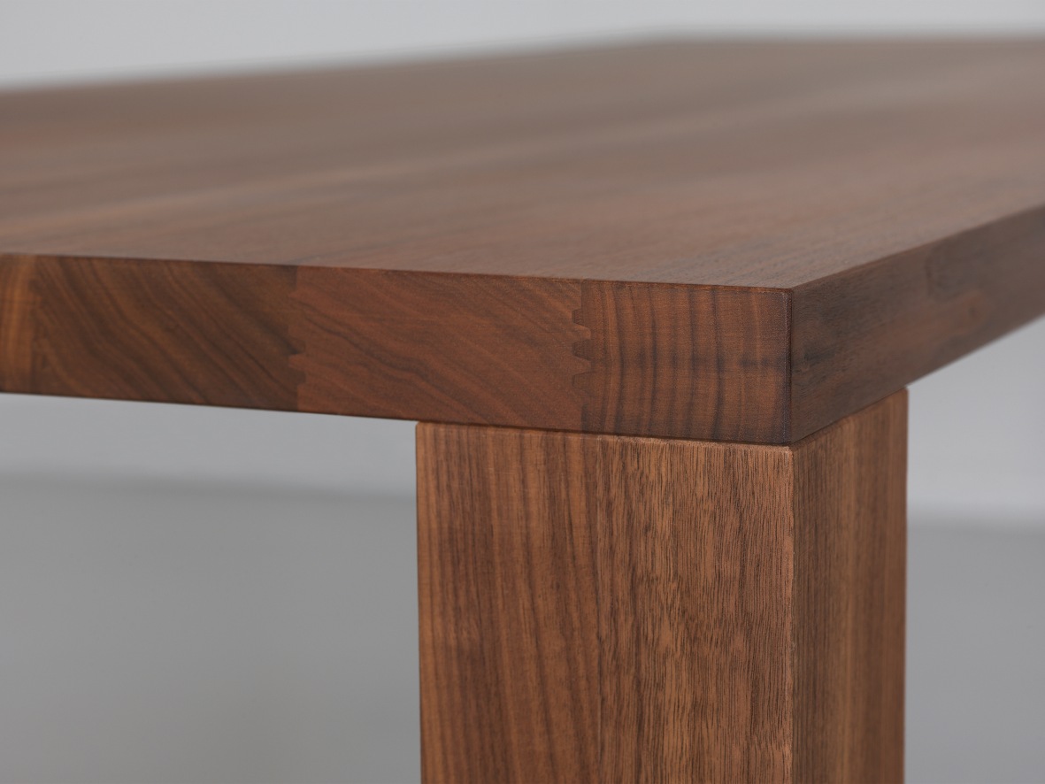 Detailaufnahme vom Pjur Esstisch: Massivholz Tischplatte und Tischbein aus Nussbaumholz.