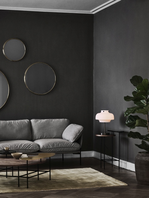 Wohnzimmer mit grauem Sofa, runden Spiegeln und AndTradition Palette Table JH25 Couchtisch aus Holz und Metall.