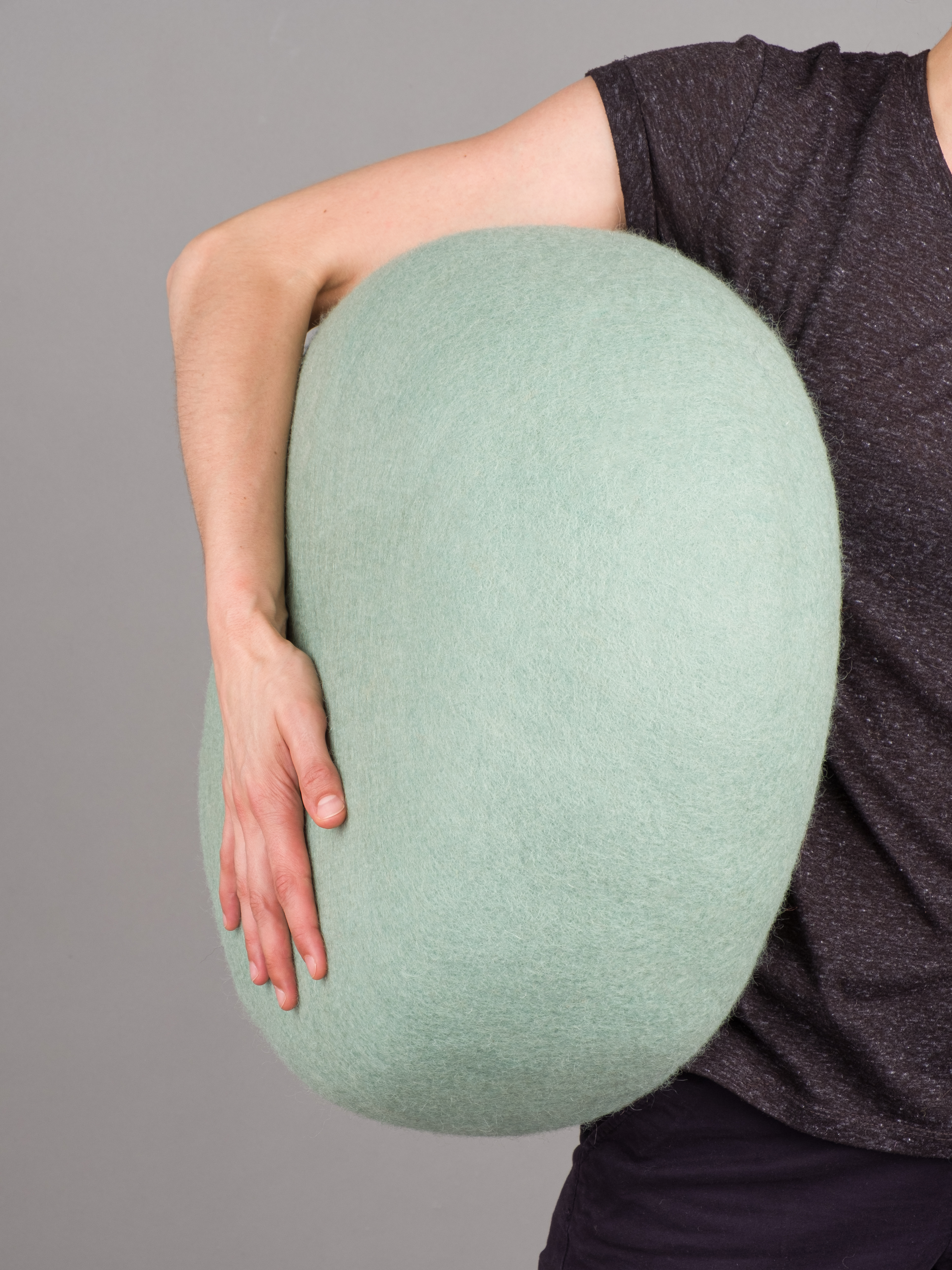 Person hält hellgrünen myfelt Filz Pouf Hocker. Gemütliches Wohnaccessoire aus Filz.