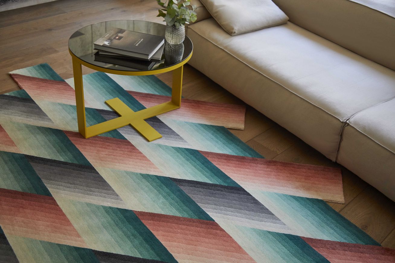 Detailaufnahme des Mirage Teppichs von Gan mit geometrischem Muster in Orange, Türkis und Grau.