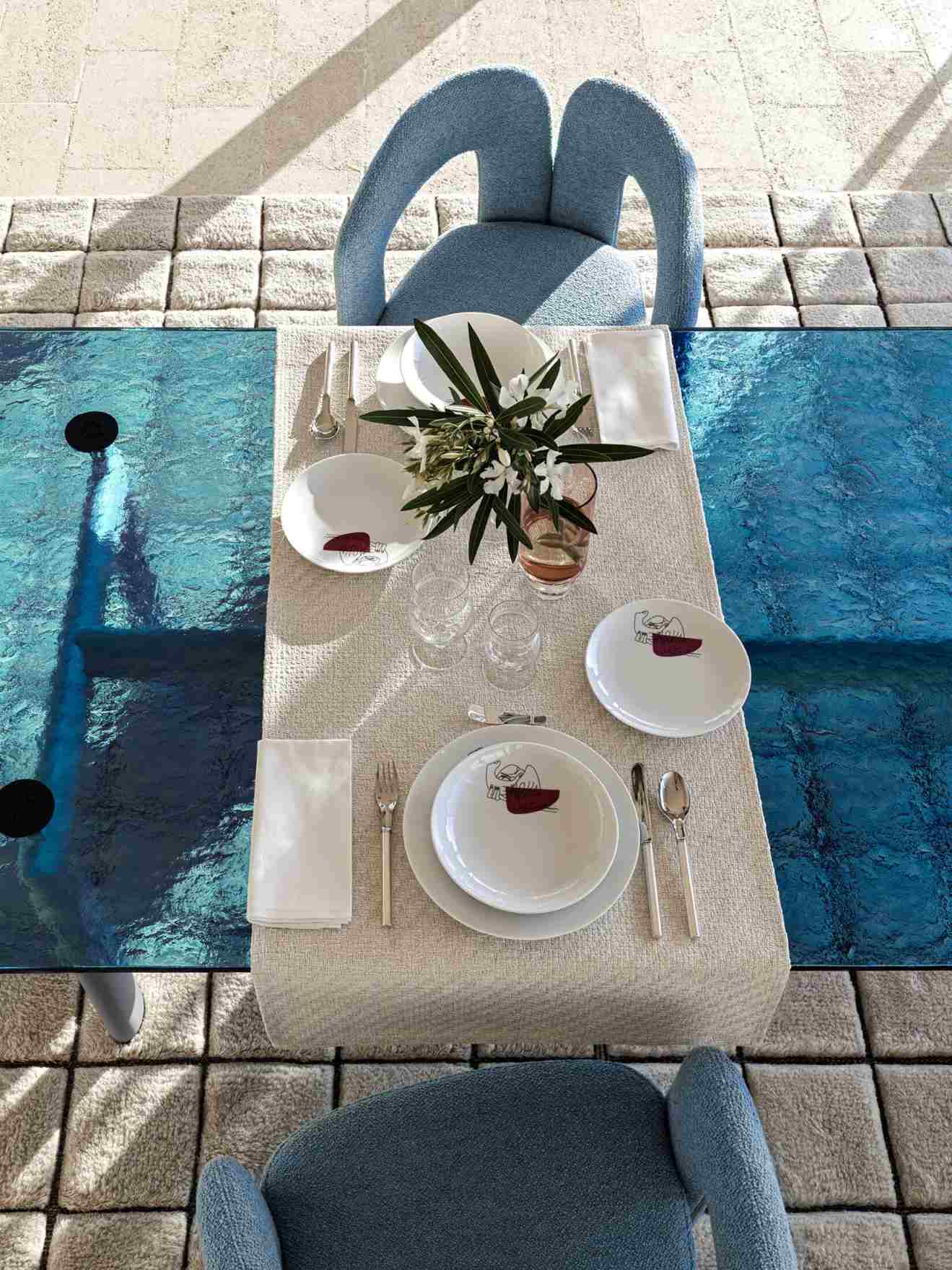 Nahaufnahme des LC6 Table tube d´avion Esstisch Cassina mit Geschirr und blauen Stühlen.