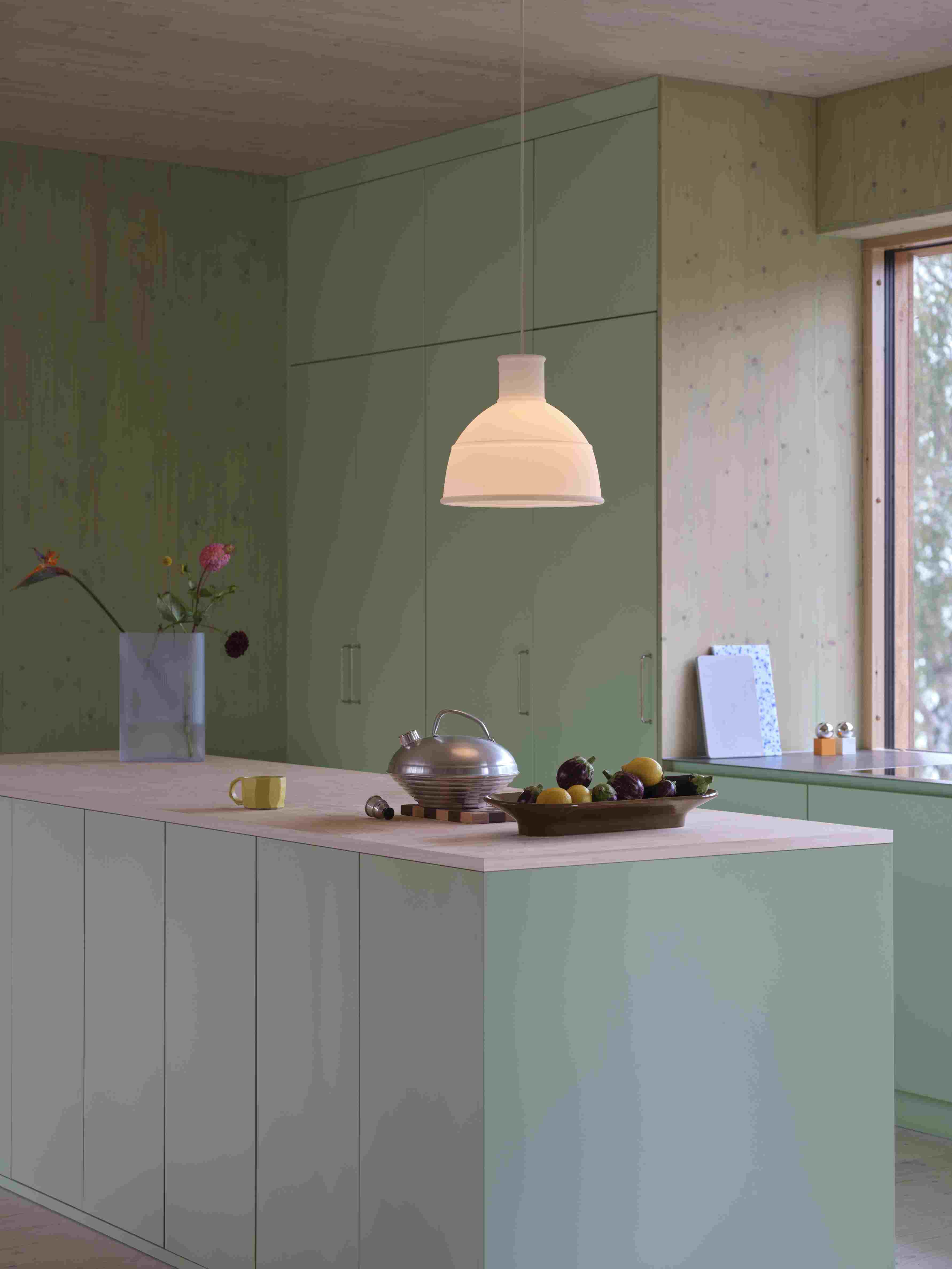 Helle Küche mit Muuto Unfold Pendelleuchte in Weiß über einer Kücheninsel, moderne Innenbeleuchtung.