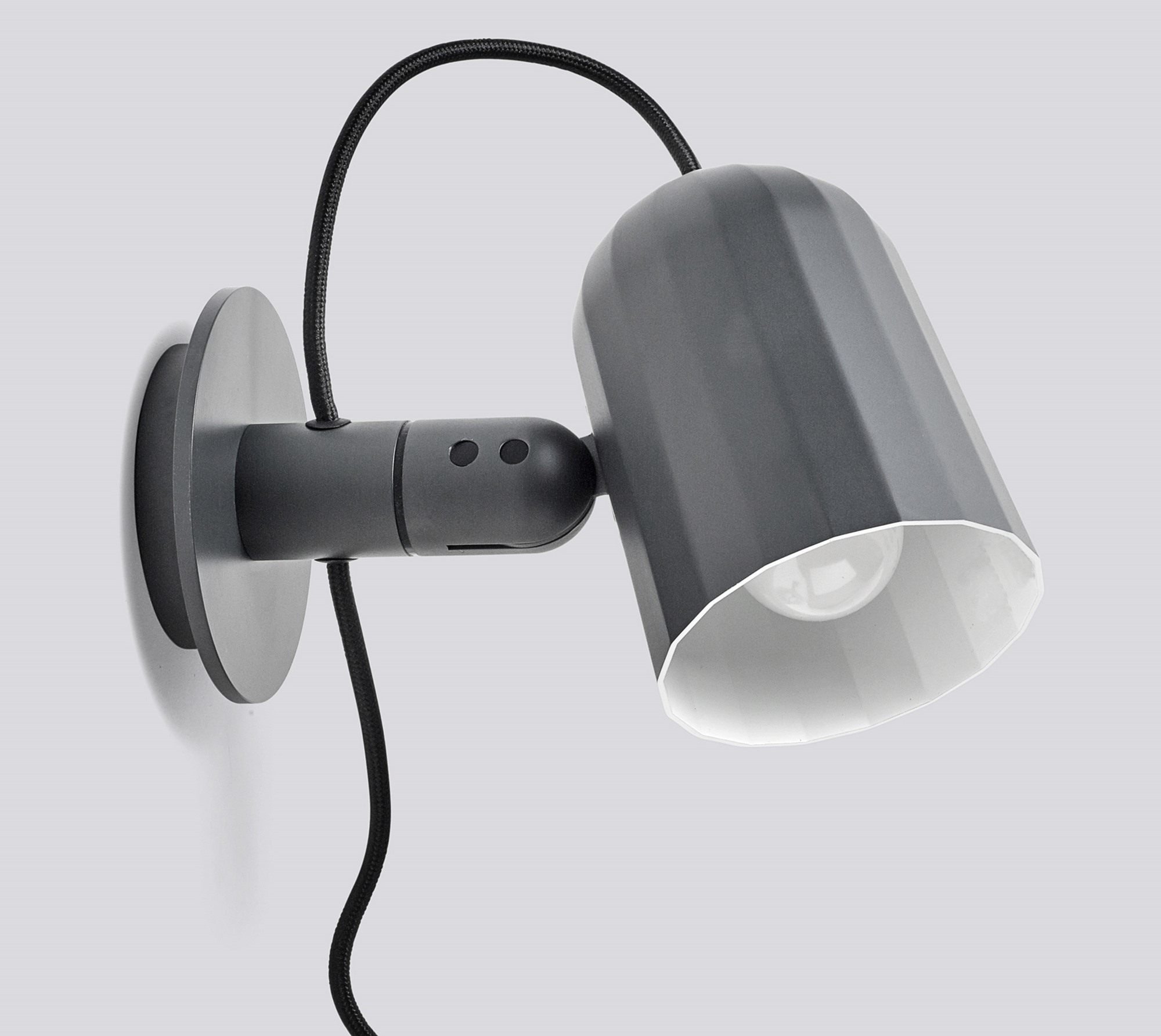 Nahaufnahme der grauen Noc Wall Wandleuchte von Hay mit schwarzem Kabel und weißem Lampenschirm.