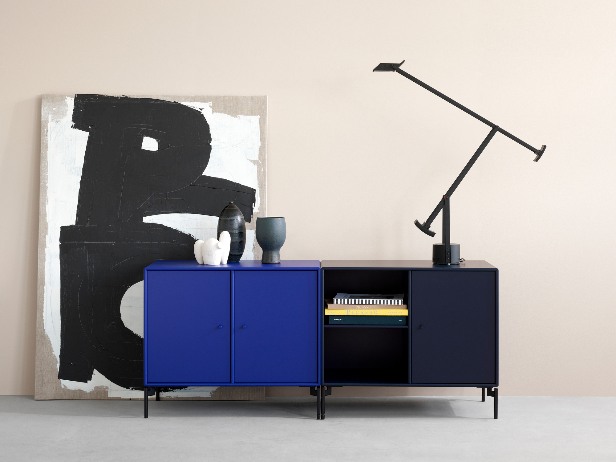 Blaues Montana Save Sideboard Low A mit schwarzen Füßen und Lampe im modernen Wohnraum.