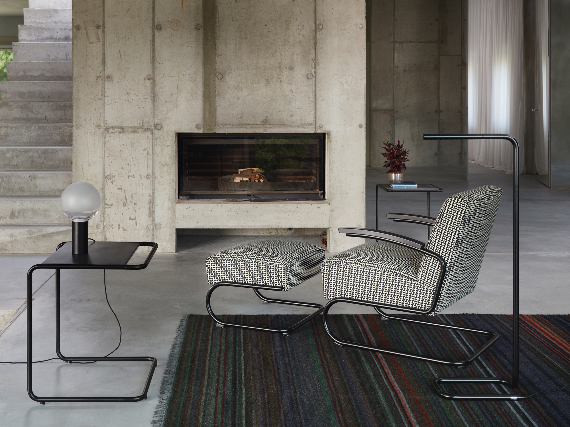 Schwarzer B97 a Thonet Beistelltisch im Bauhaus-Stil neben Sessel und Lampe im Wohnzimmer.