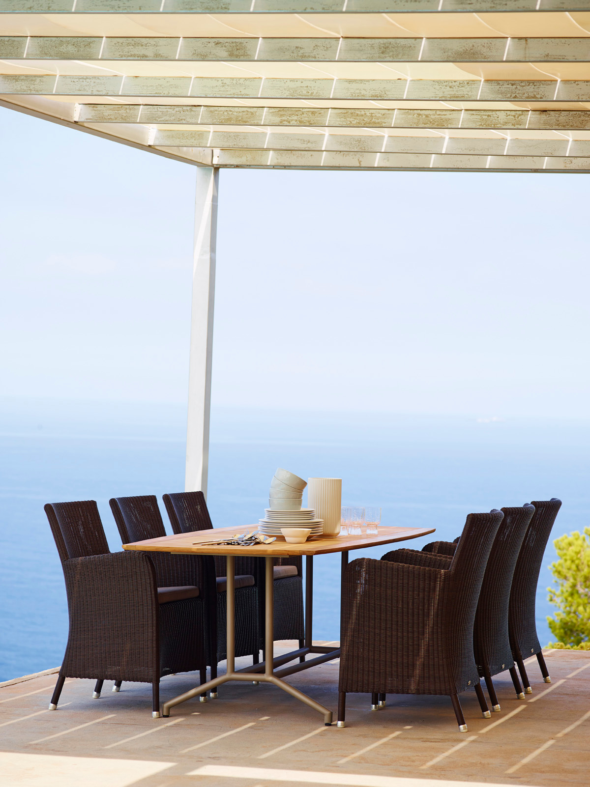 Esstisch mit schwarzen Cane-Line Outdoor Sesseln aus Rattan vor Meerblick. Gartenmöbel für Terrasse.