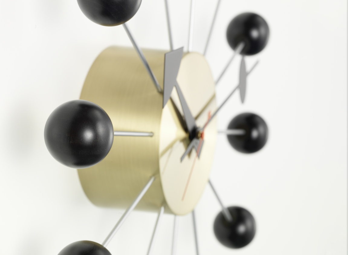 Detailaufnahme der Vitra Ball Clock Wanduhr in Schwarz mit goldenem Gehäuse.