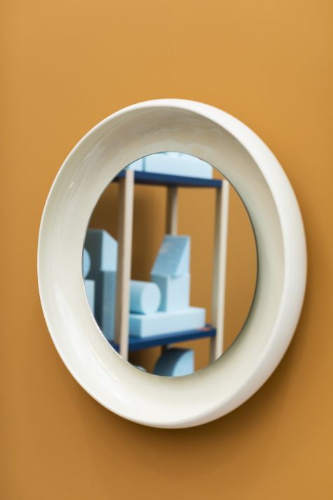 Runder Coque Spiegel von Miniforms mit weißem Keramikrahmen an ockerfarbener Wand.