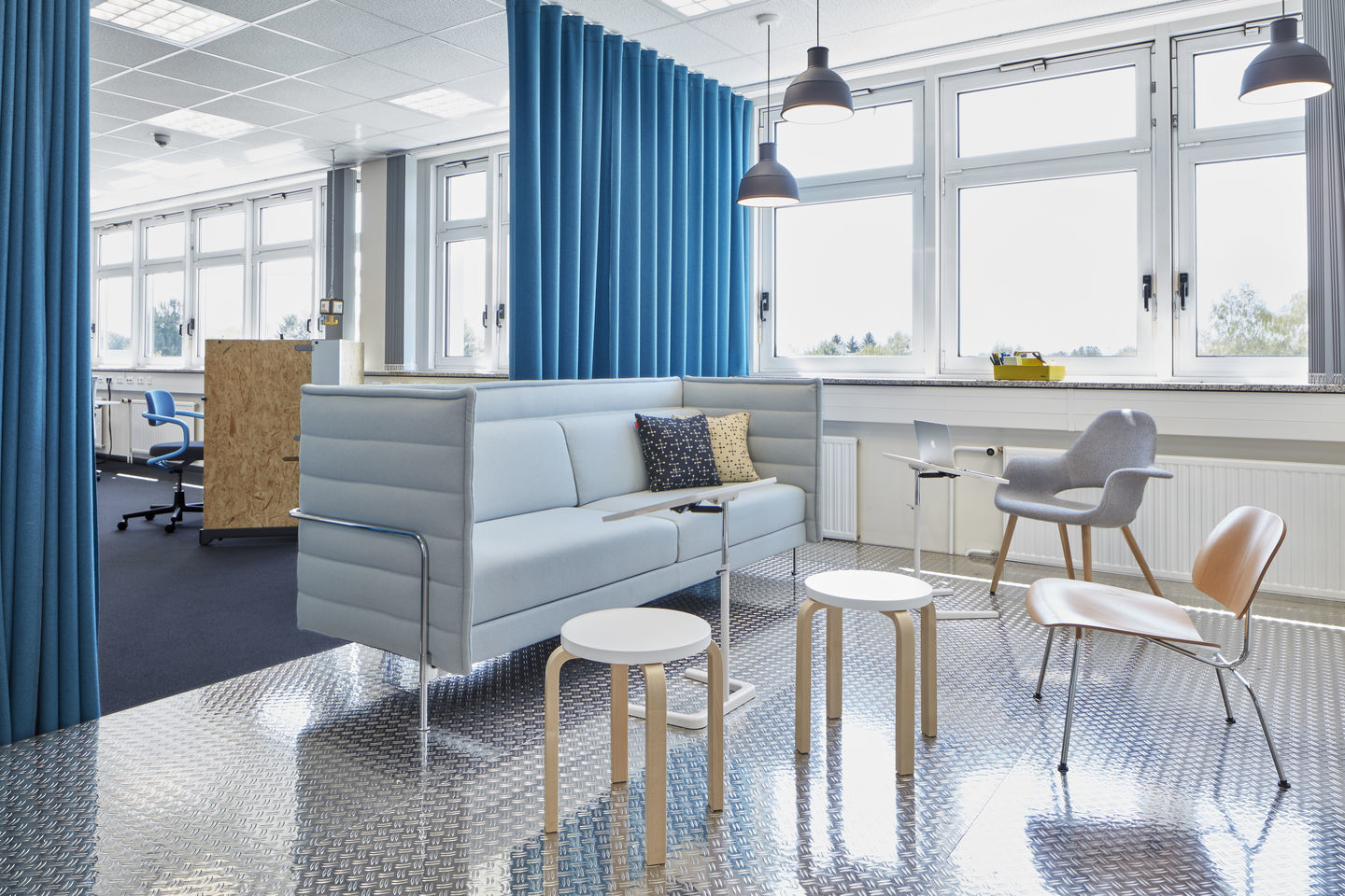 Büro-Szene mit Vitra Plywood Group LCM Stuhl, Sitzgelegenheiten und Tageslicht für moderne Arbeitsumgebung.