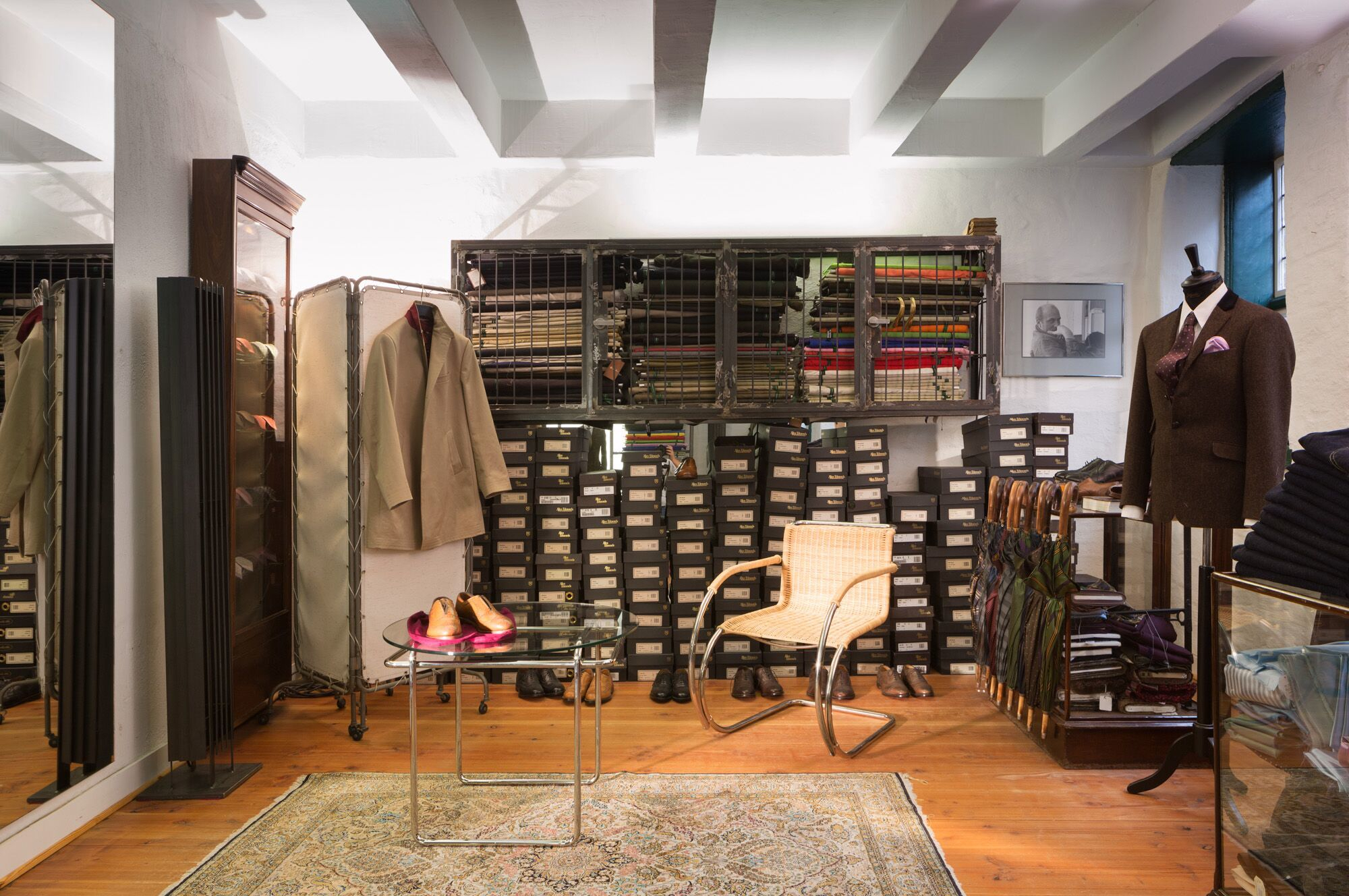 Weißenhof Armlehnenstuhl D42 Tecta aus Rattan im Interieur eines Bekleidungsgeschäfts mit Kleidung, Schuhen und Accessoires.