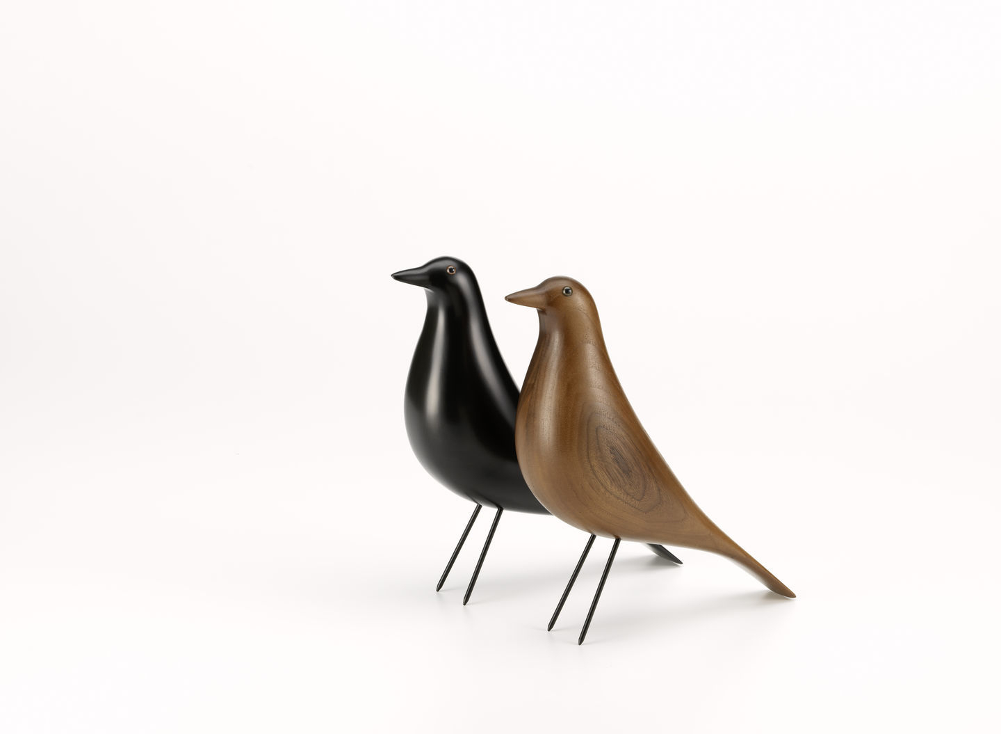 Zwei Eames House Bird Skulpturen, eine aus schwarzem Holz, eine aus Nussbaumholz, von Vitra.