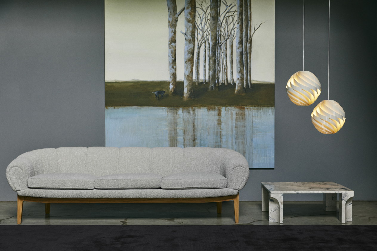 Zwei moderne Gubi Turbo Pendelleuchten über einem Wohnzimmer mit Sofa, Tisch und Kunstwerk.