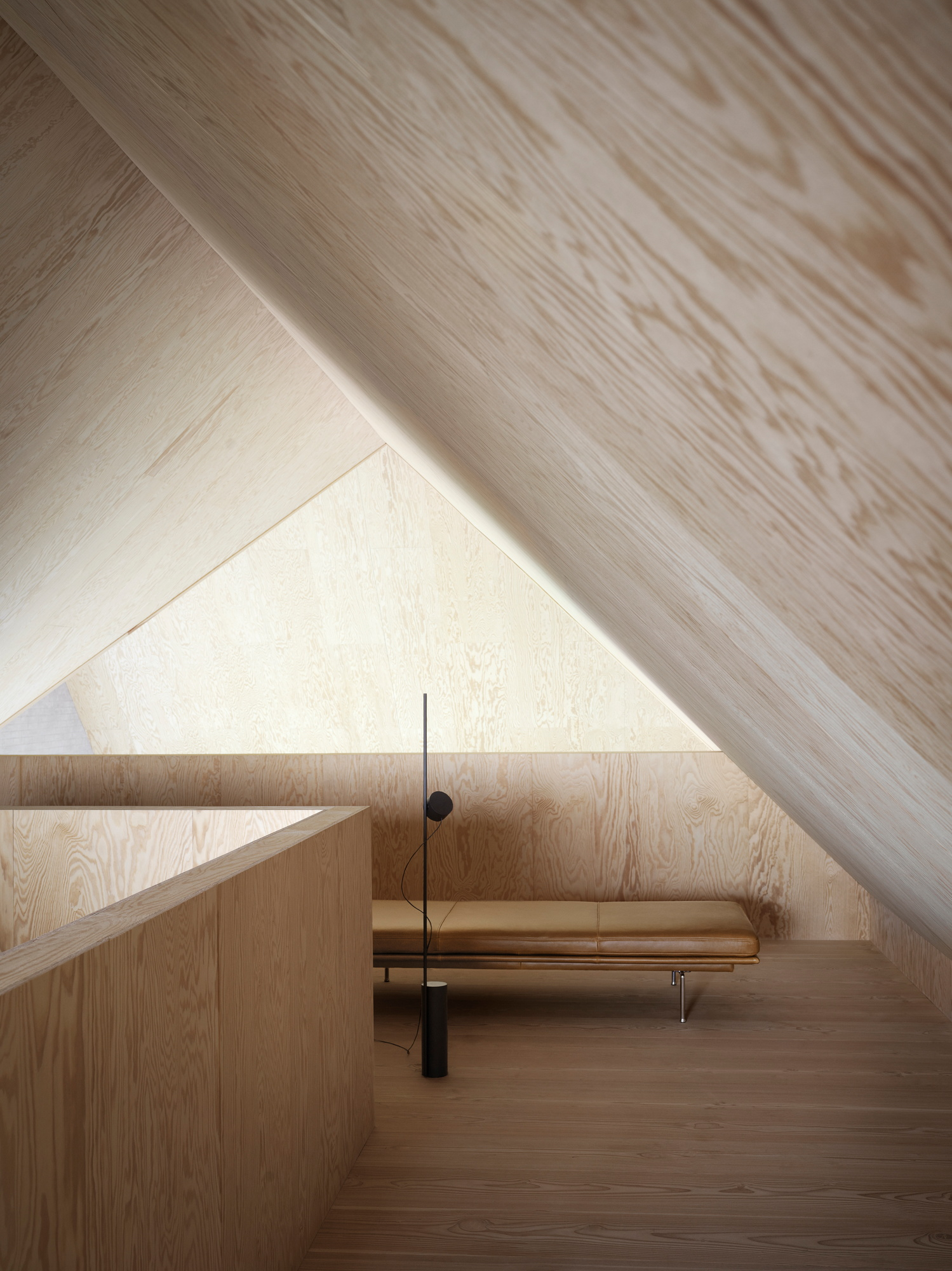 Outline Daybed Liege von Muuto in hellem Dachgeschoss mit Holzverkleidung und Stehlampe.
