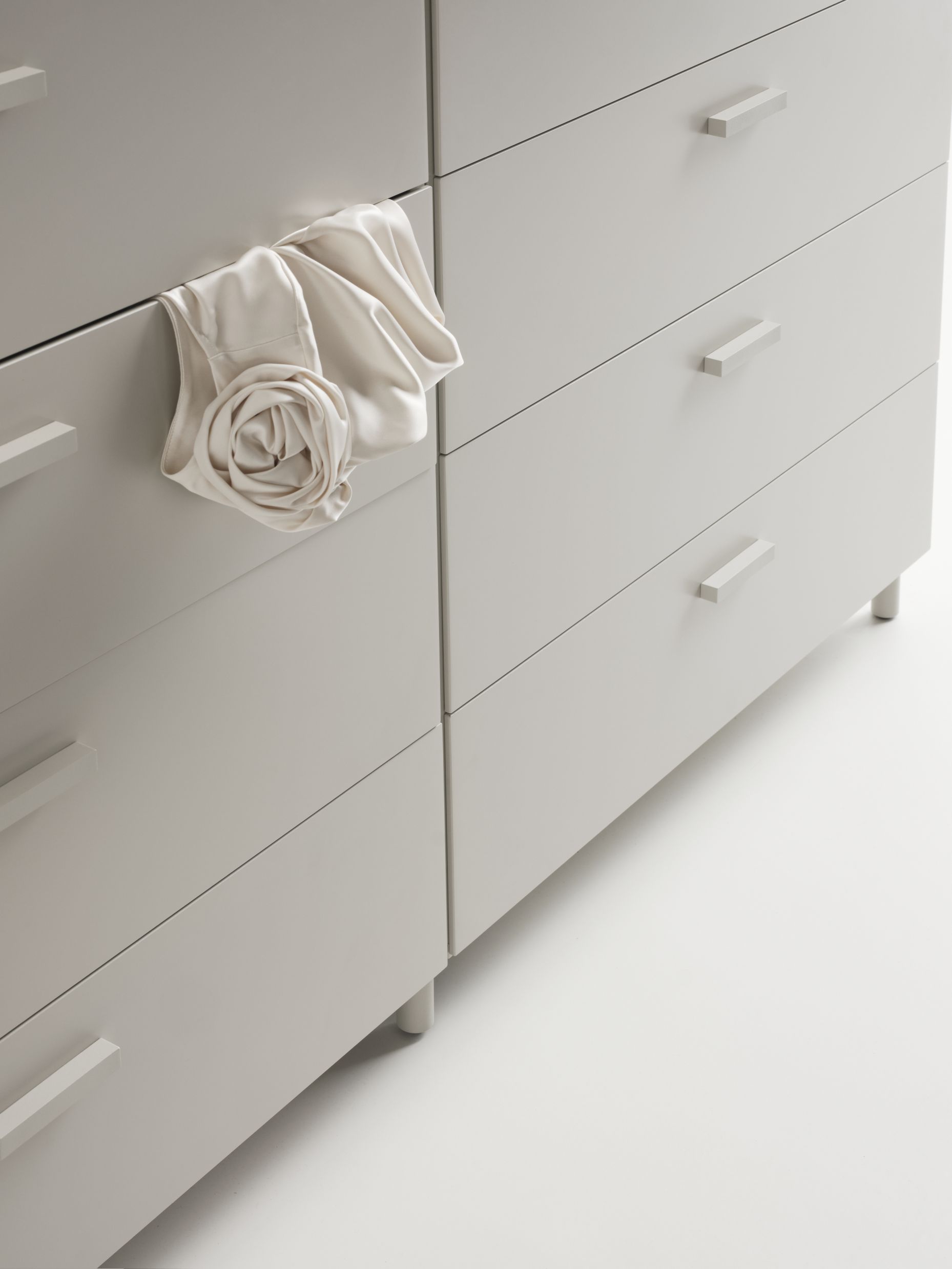 Detailaufnahme einer Relief Kommode von String Furniture mit Sockel und hellem Stoff.