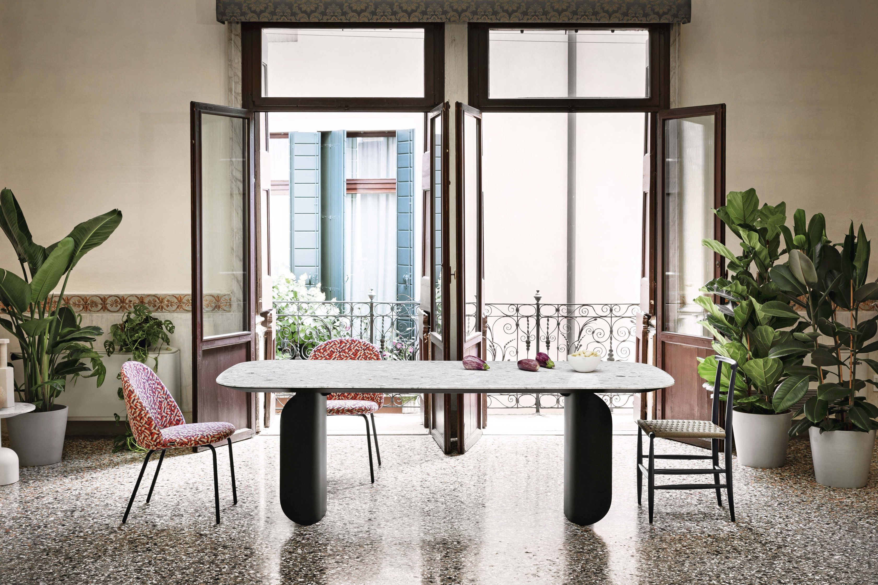 Barry Palladio Moro Marmortisch von Miniforms in einem hellen Raum mit Stühlen und Pflanzen.