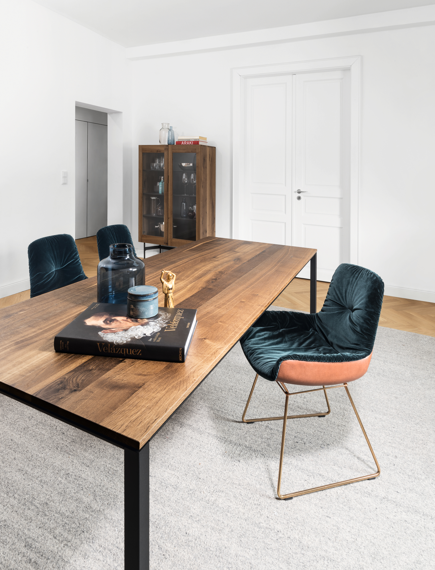 Janua S 600 Tisch Nussbaum mit schwarzen Beinen und blauen Stühlen in modernem Esszimmer.