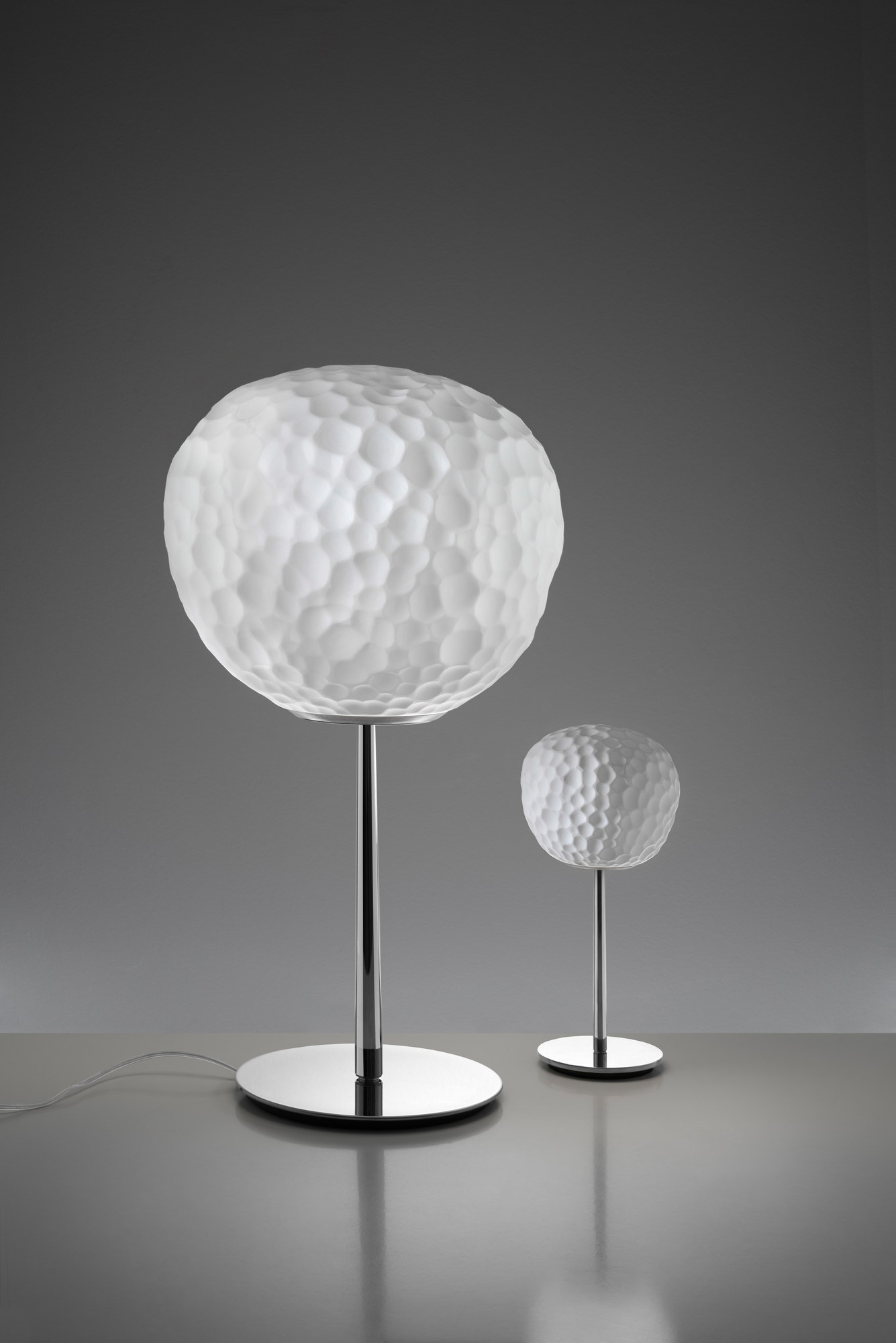 Meteorite Tischleuchte von Artemide: Zwei moderne Lampen mit strukturiertem, weißem Glas und Chromfuß.