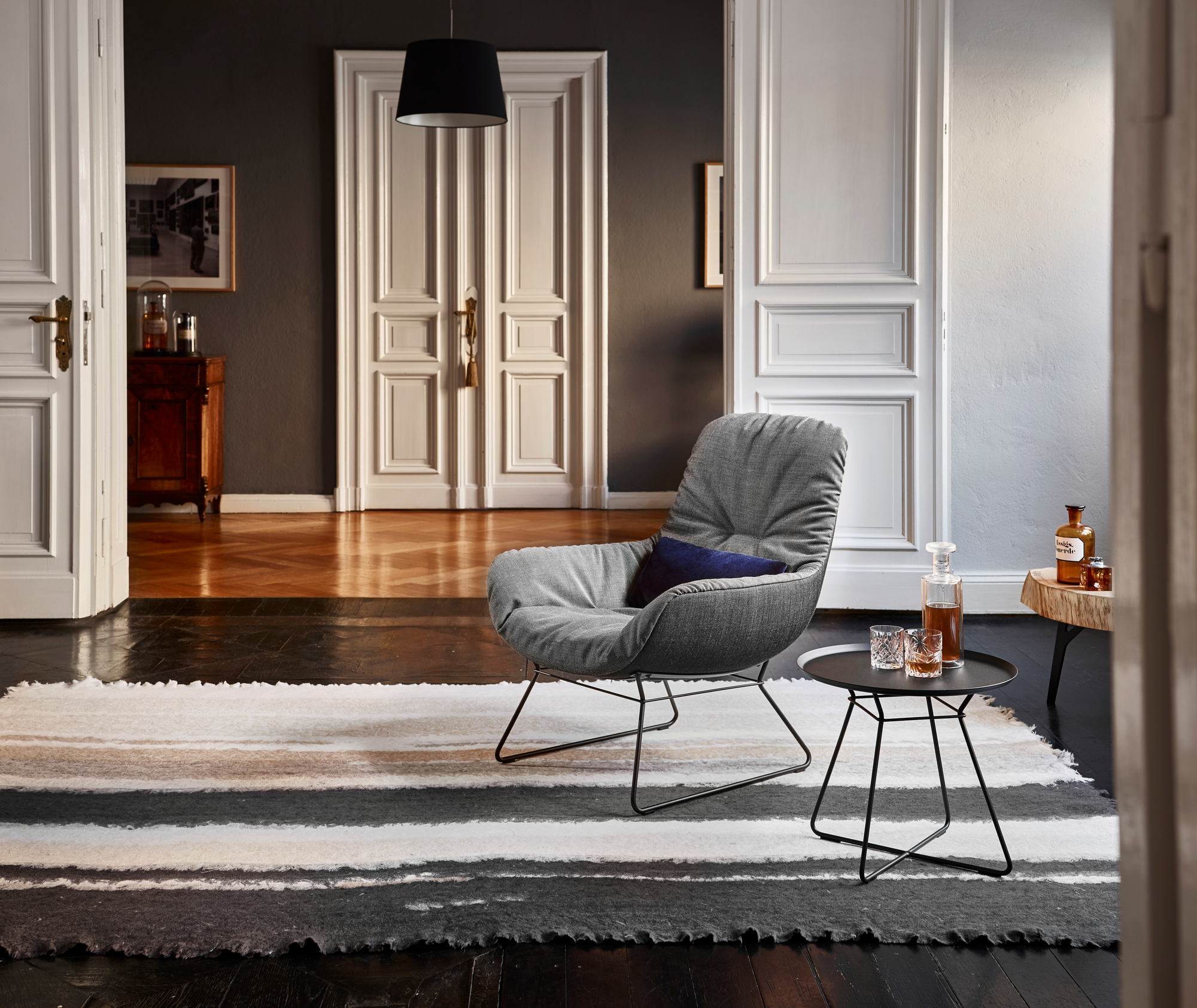 Leya Small Beistelltisch von Freifrau Manufaktur neben Sessel mit Getränken im stilvollen Wohnzimmer.