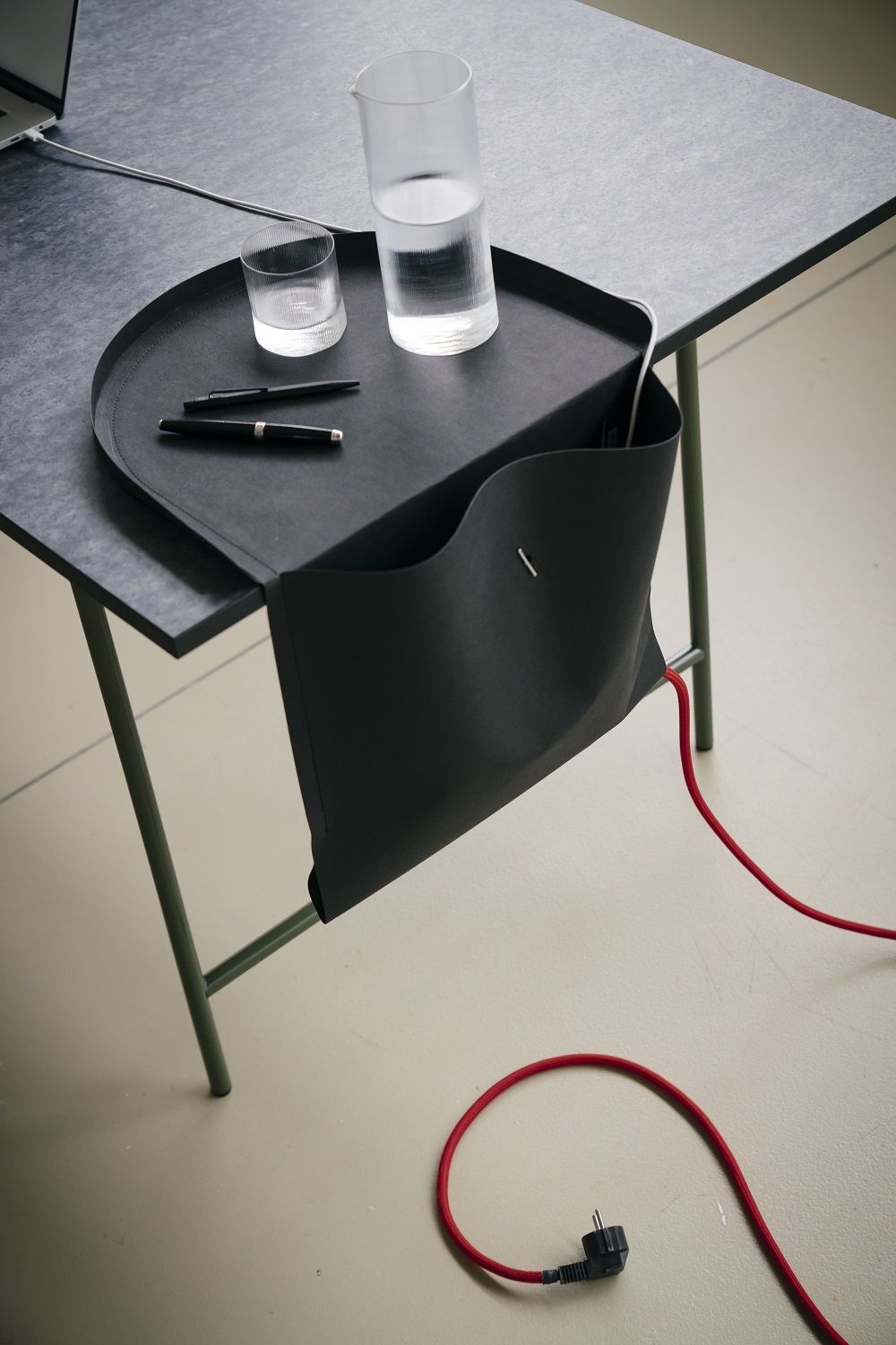 Schwarzer Salto Organizer von Richard Lampert am Schreibtisch, mit Stiften und Wassergläsern. Papiermöbel für Büro und Homeoffice.