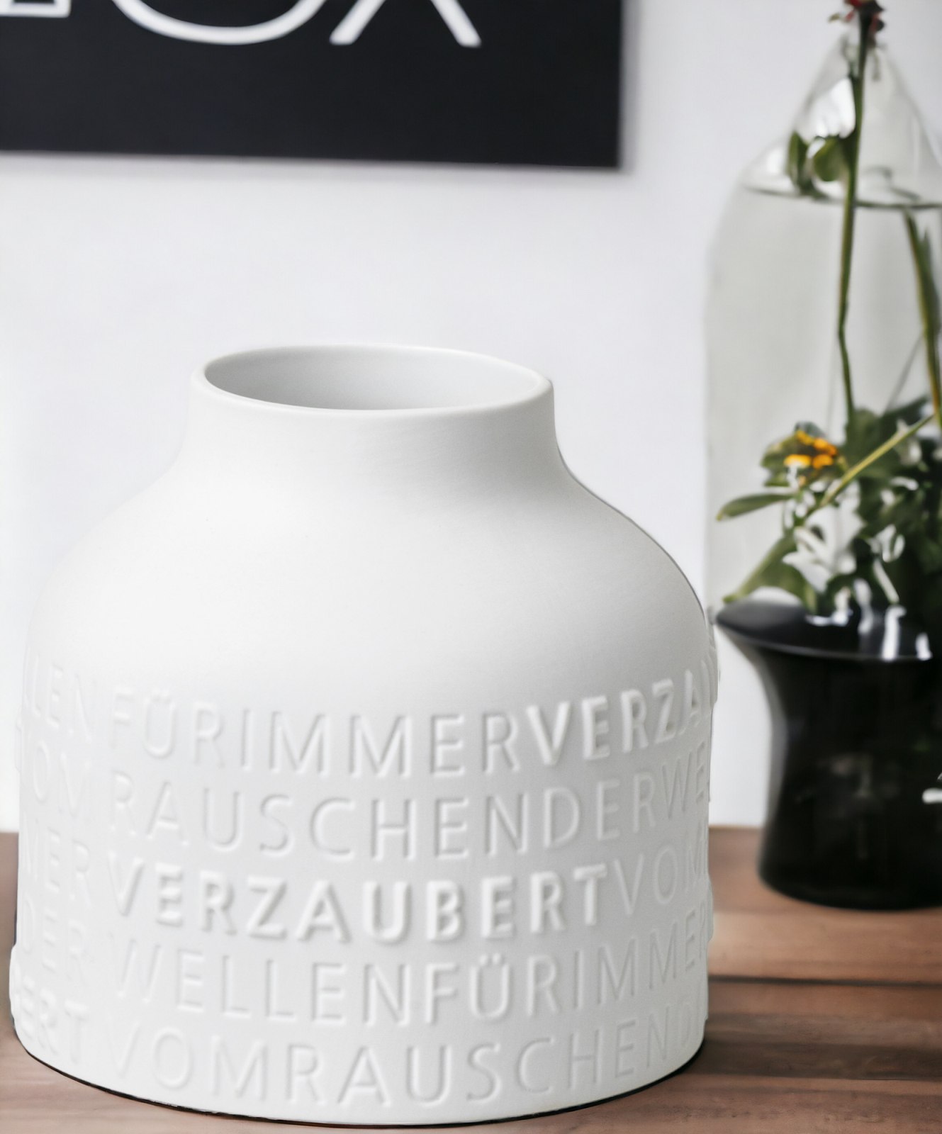 Nahaufnahme der weißen "Für immer verzaubert" Vase mit geprägten Schriftzug, dekorative Keramik für Blumen.